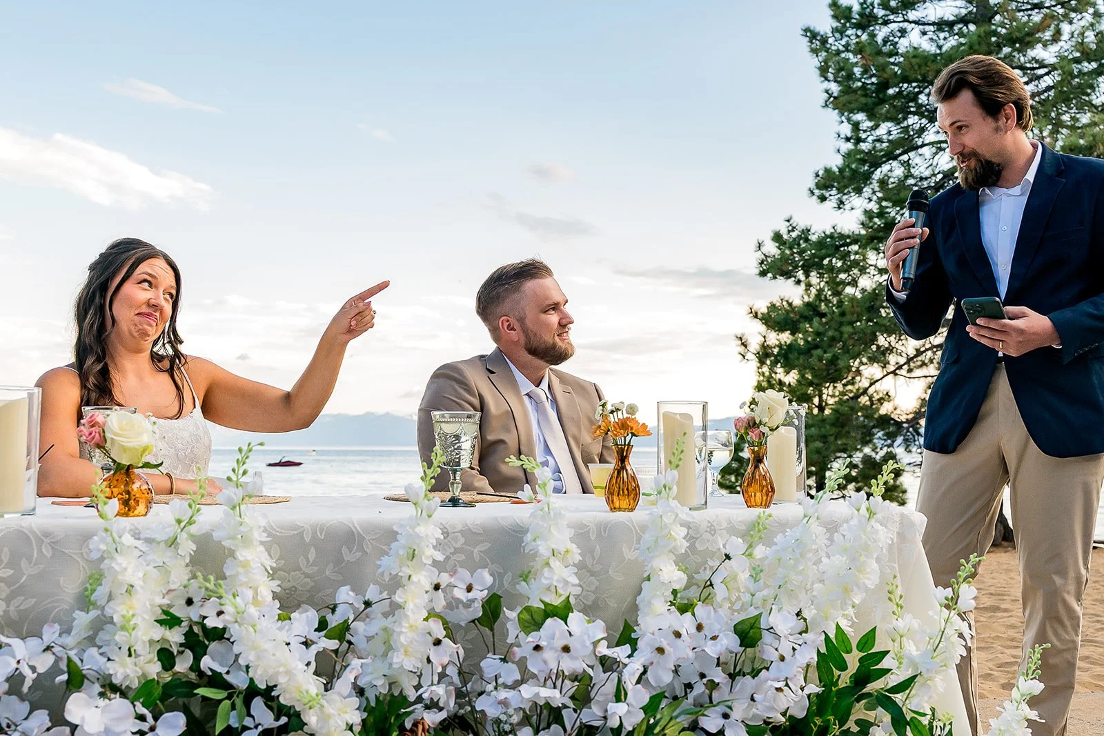  A bride and groom smile at someone toasting them with Lake Tahoe in the background at the North Tahoe Event Center in Kings  Beach, California. 