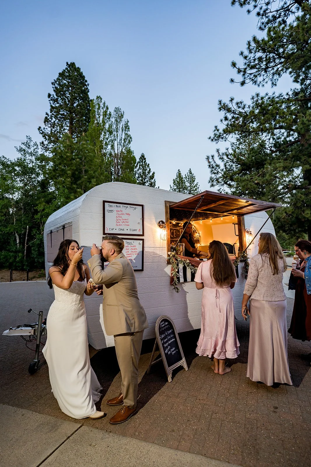 A bride and groom eat ice cream in front of a vintage trailer at the north tahoe events center in kings beach, california.