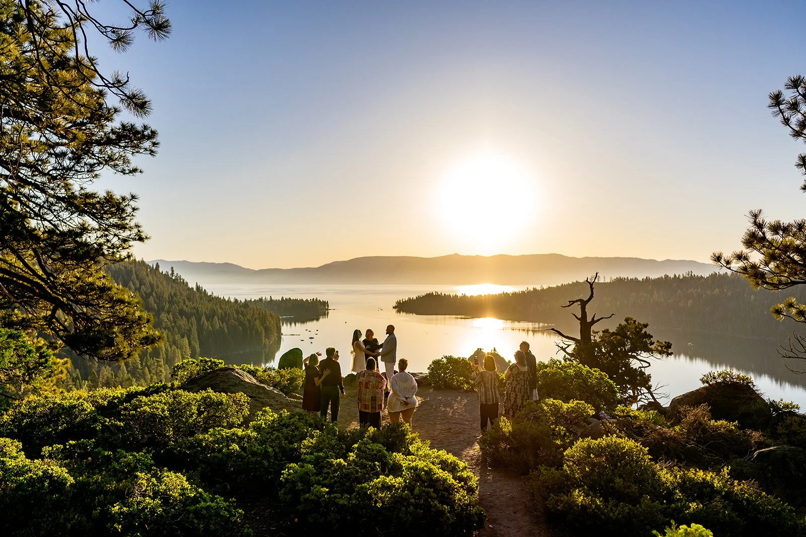Golden light shines on Lake Tahoe while a wedding couple holds hands in front of Emerald Bay photographed by Lake Tahoe wedding photographer Nicky Byrnes Photography