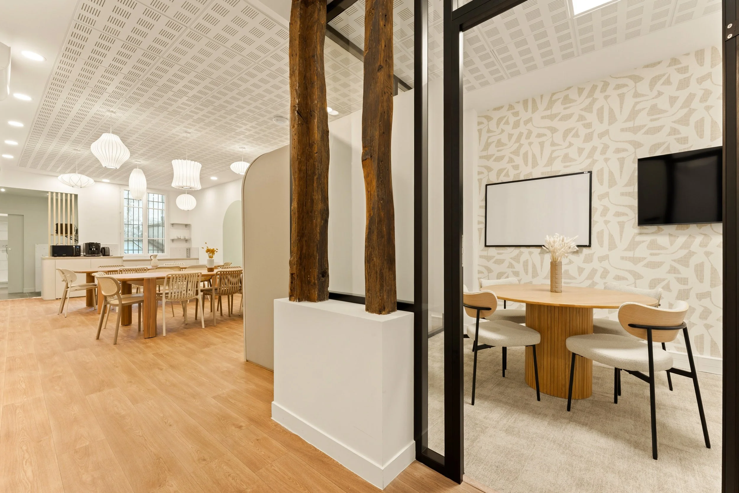 Intérieur moderne avec espace de bureau à gauche et espace de rangement en bois claire à droite, décor minimaliste avec plantes et objets décoratifs.