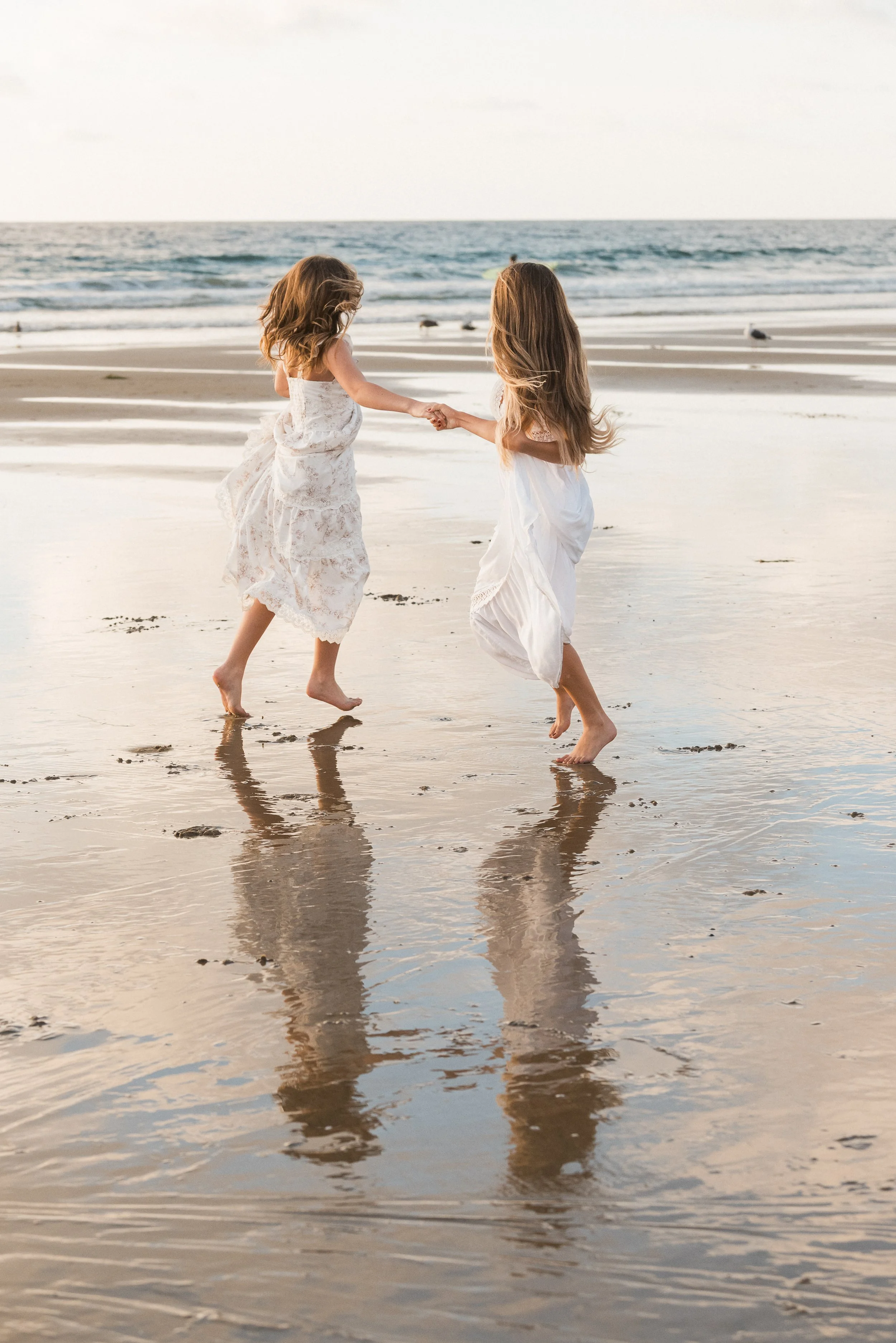 A couple embracing on the beach near the ocean, with waves in the background.