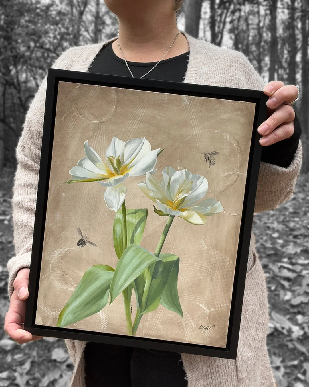 The artist holds a framed painting of two full open white tulips. Two bees are flying nearby while an art climbs up the stem.