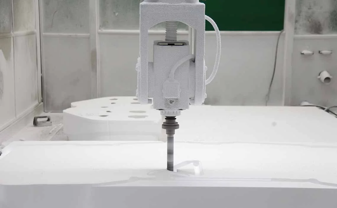 Fresa CNC in azione su un blocco di polistirolo, durante una lavorazione di sagomatura e intaglio di precisione.