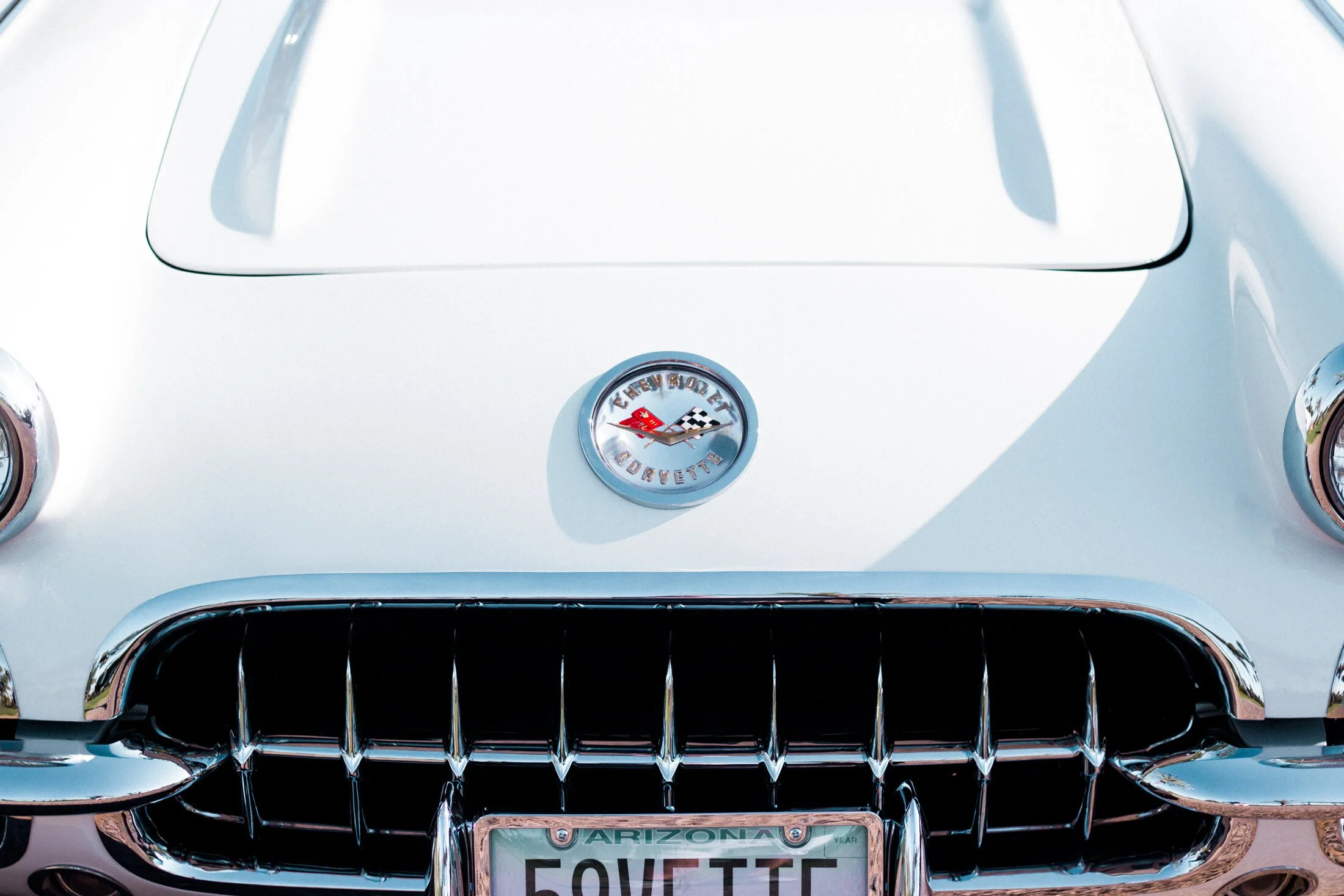 Front view of a classic white and turquoise 1959 Corvette convertible with an Arizona license plate, featuring the Corvette emblem and chrome details.