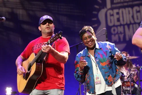 A man playing guitar and a woman singing or dancing on stage during a live performance.
