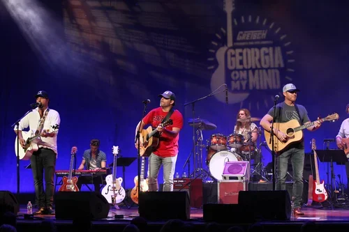 Band performing on stage with multiple musicians, guitars, and drums at the Georgia on My Mind event.