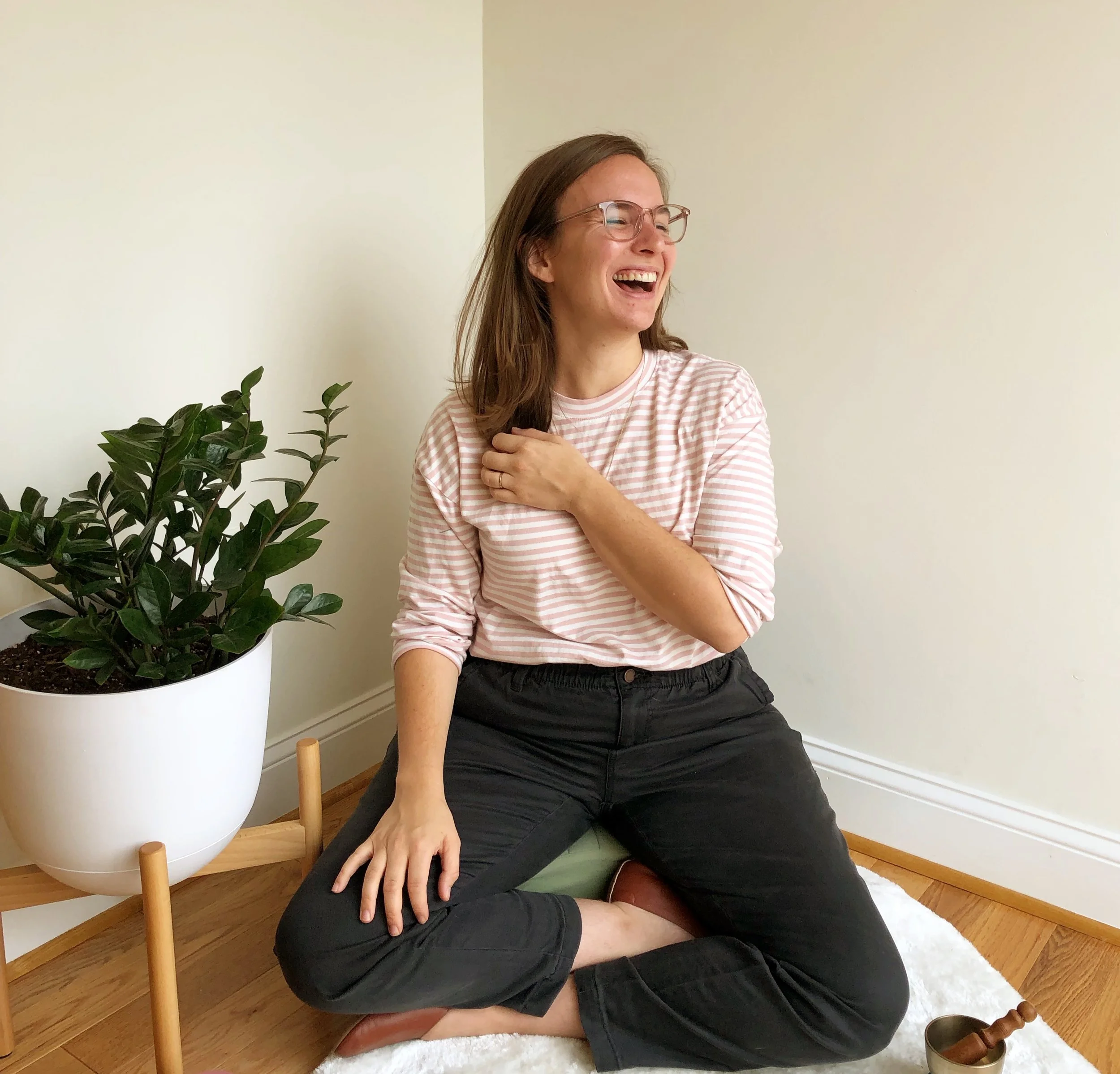 A pic of ellie miller laughing next to plants, smiling. To illustrate her web design business for therapists and coaches that also sells squarespace templates for therapists and coaches
