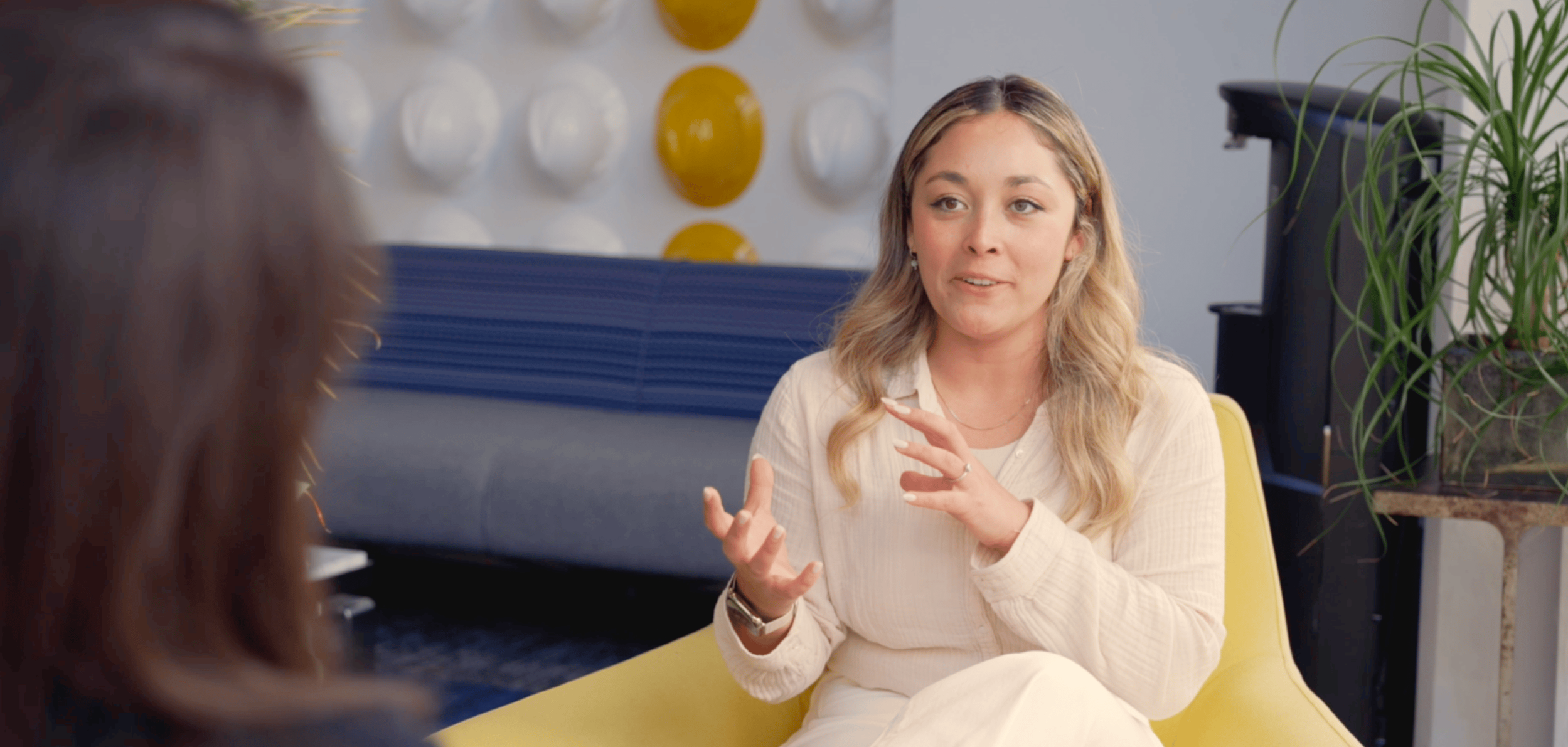 On-camera interview subject speaking candidly in modern branded interview setting — corporate video production
