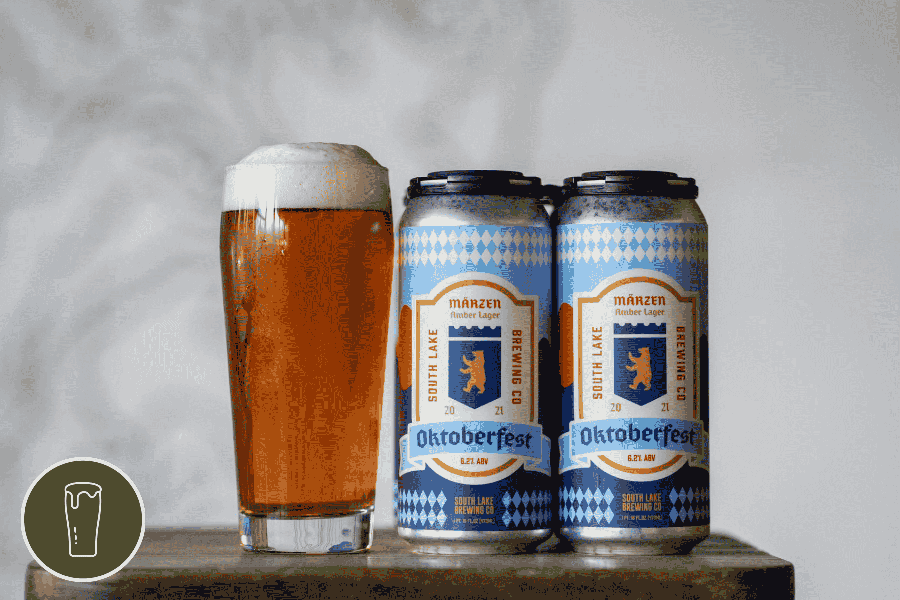 four pack and pint of Marzen amber lager on a wooden table in front of a gray background