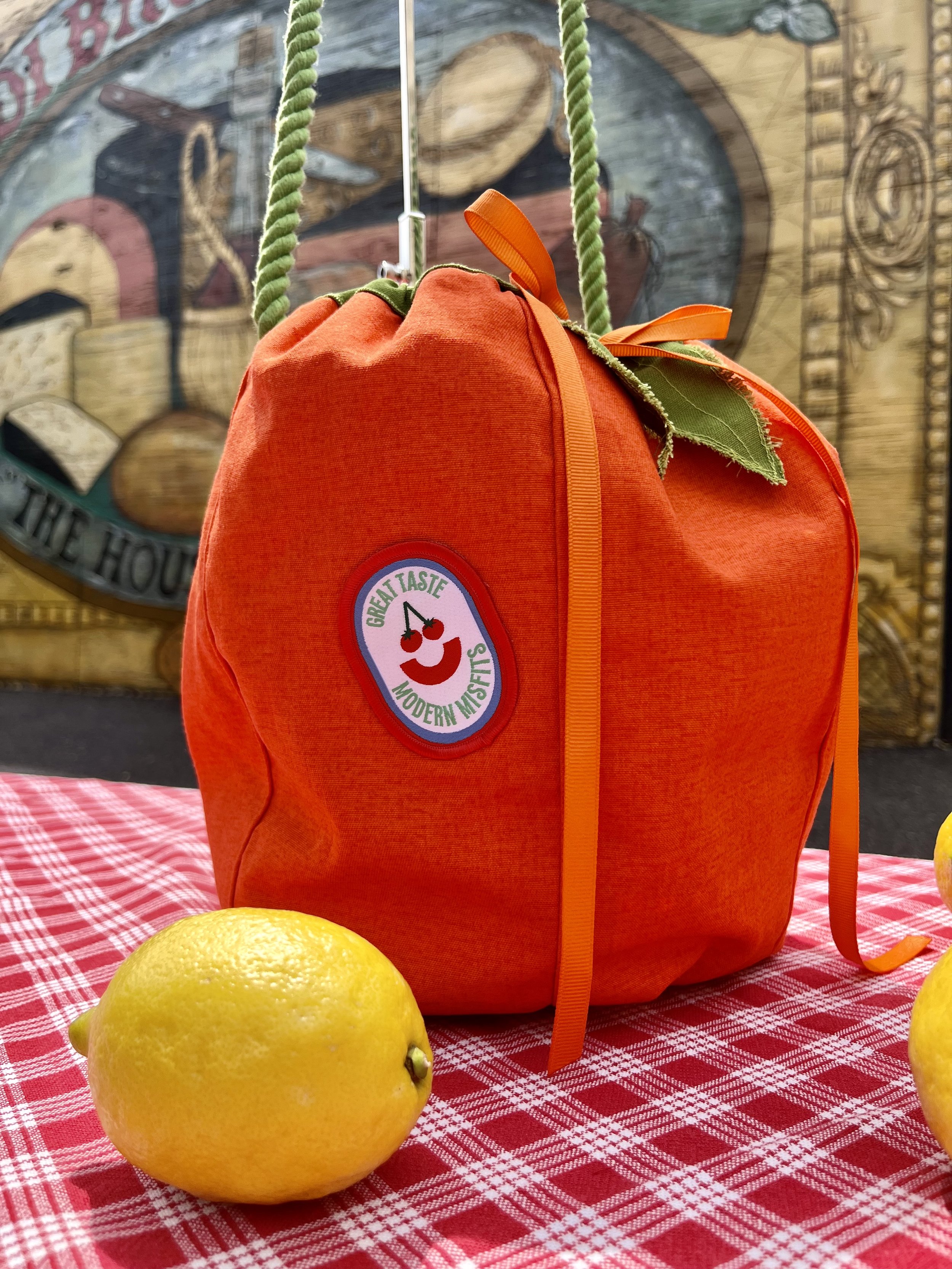 Roung orange shaped bag on red gingham tablecloth