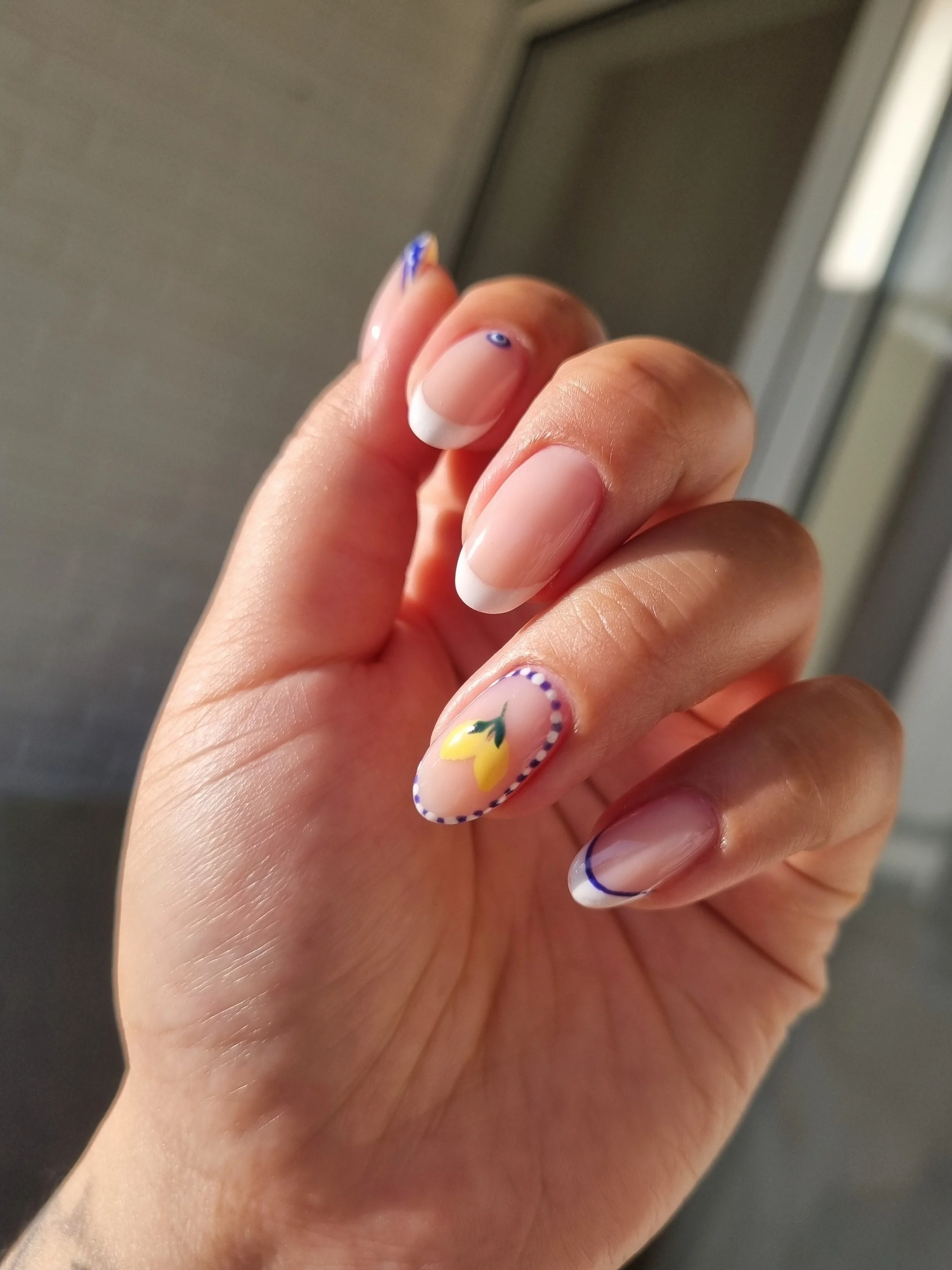 Nærbillede af en hånd med french manicure og en enkelt negl med blomsterdesign.