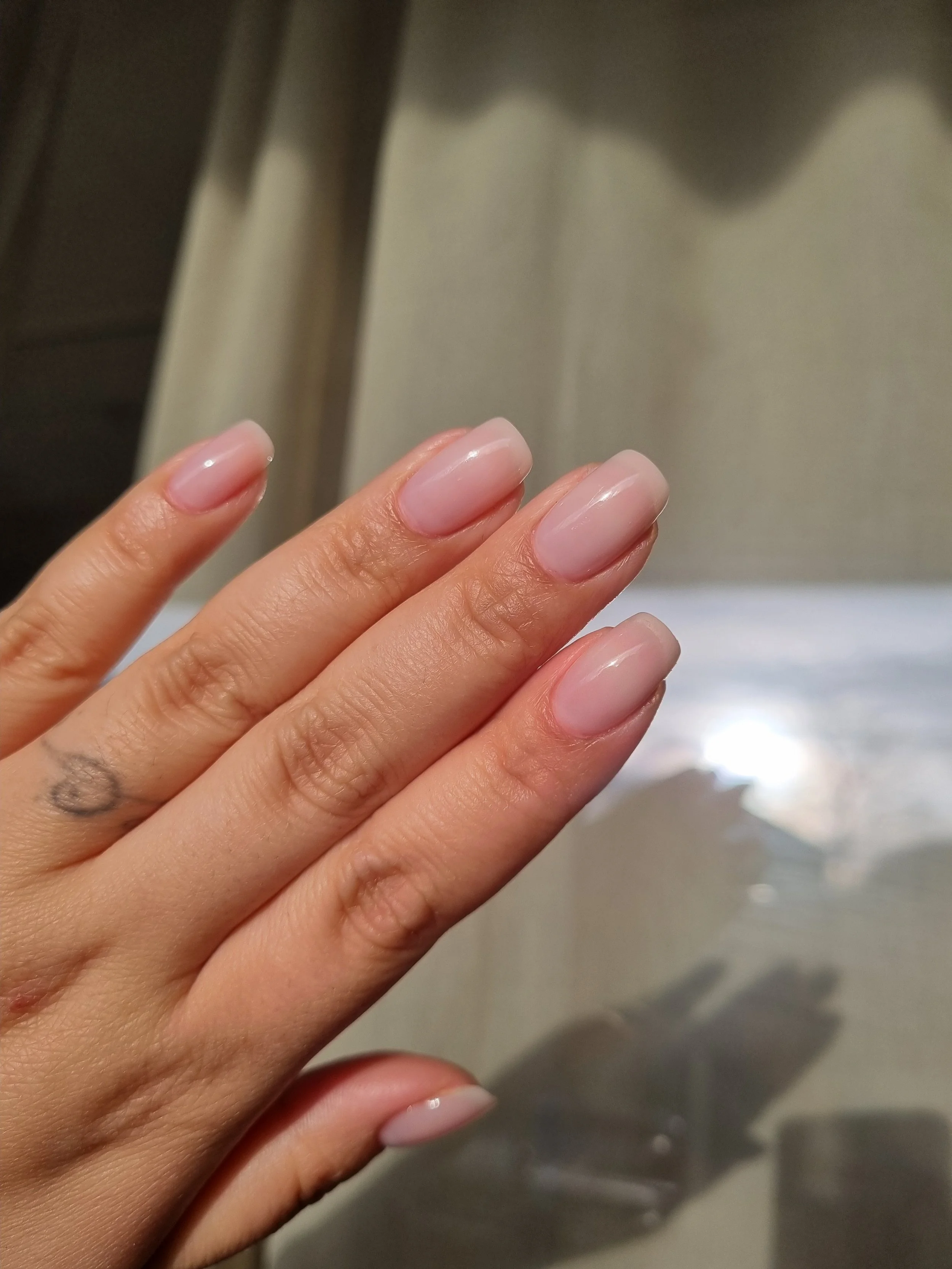 Nærbillede af en hånd med nylakerede, lyserøde negle.