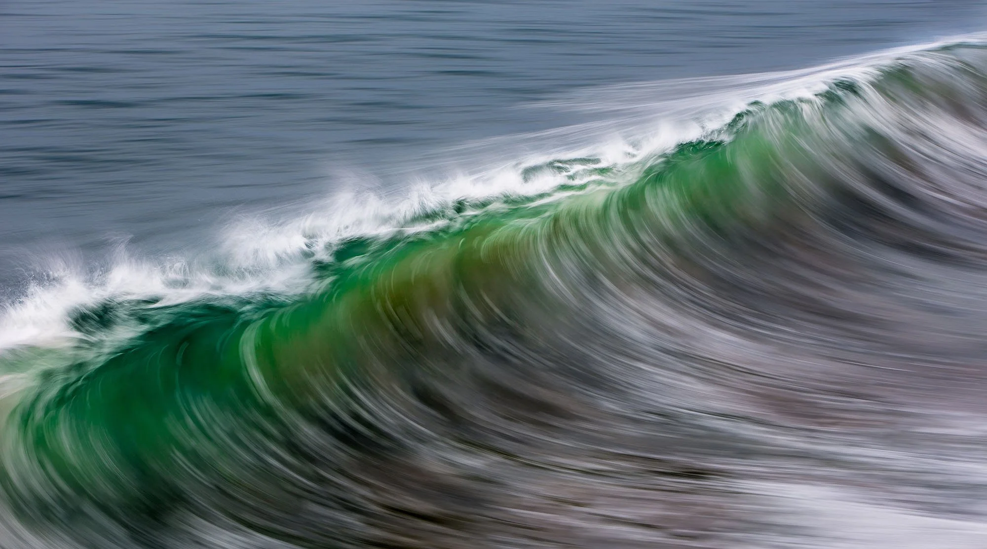 A large ocean wave with green and white foam.