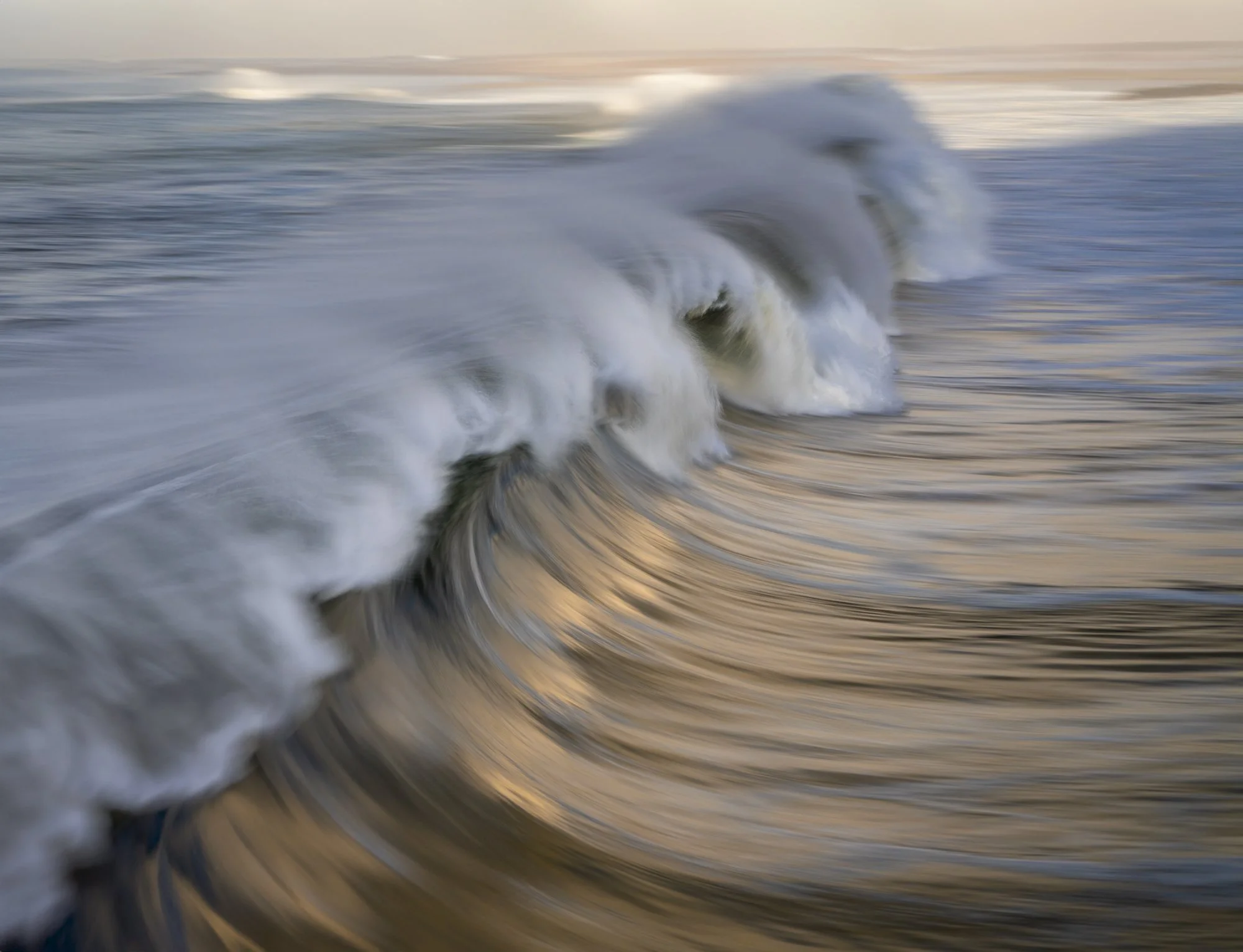 Blurry photo of ocean waves at sunset or sunrise.