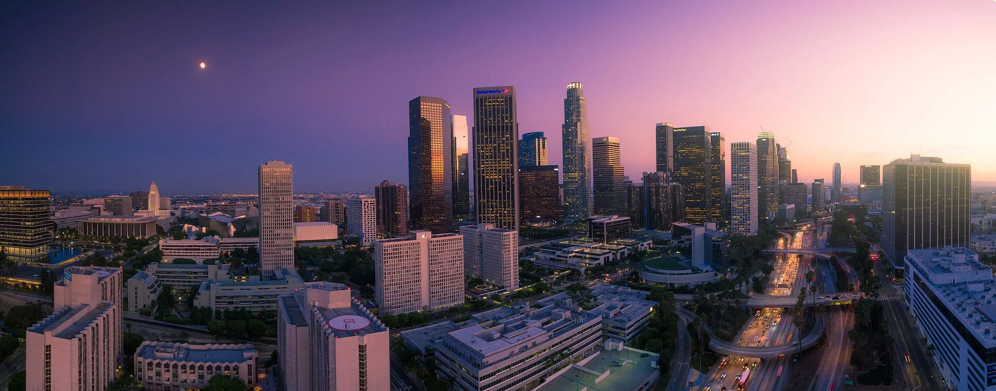 Skyline of Los Angeles at sunset with skyscrapers and a full moon in the sky