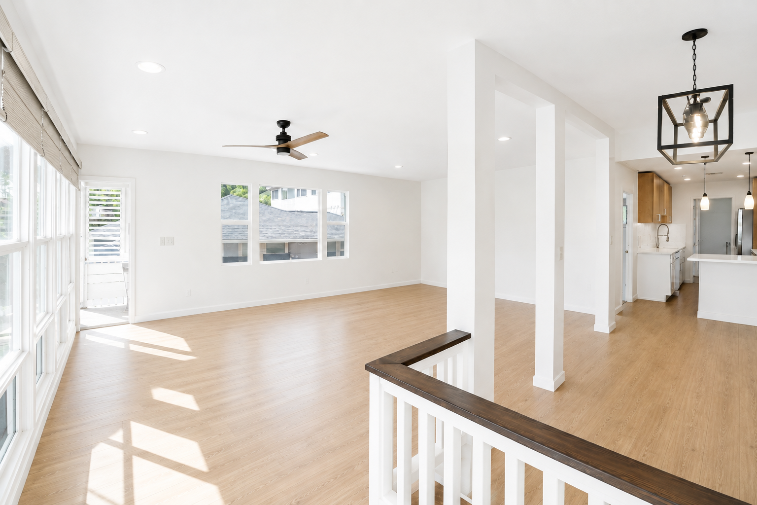 Hawaii Real Estate Photography:  Empty living room with large windows, white walls, wood flooring, and a ceiling fan.