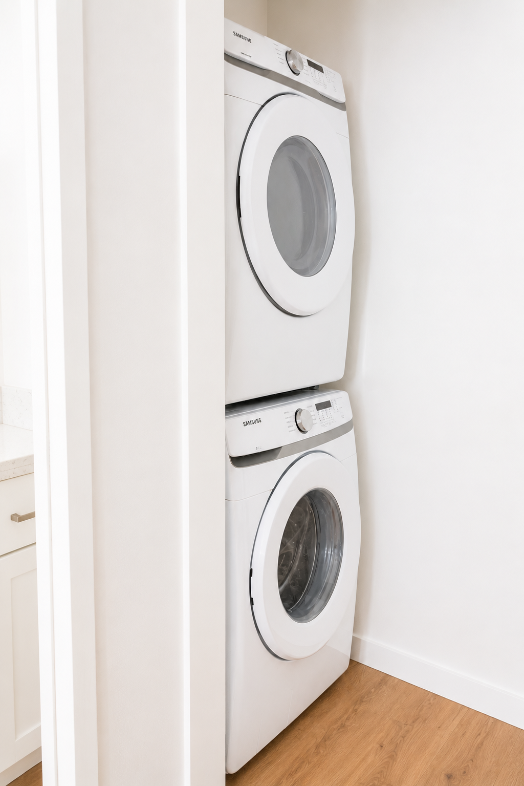 Stacked white Samsung front-loading washer and dryer in a laundry room.