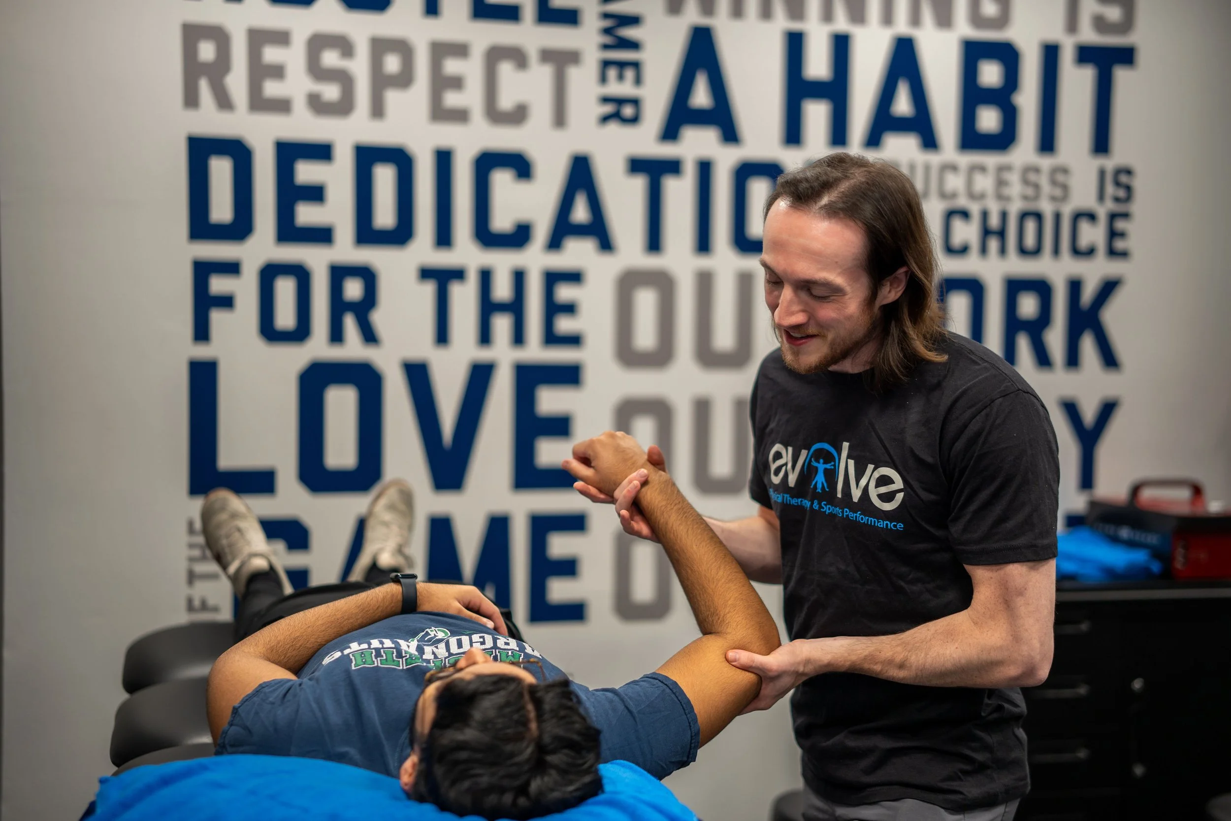 A physical therapist working on a patient's arm/shoulder in a physical therapy clinic