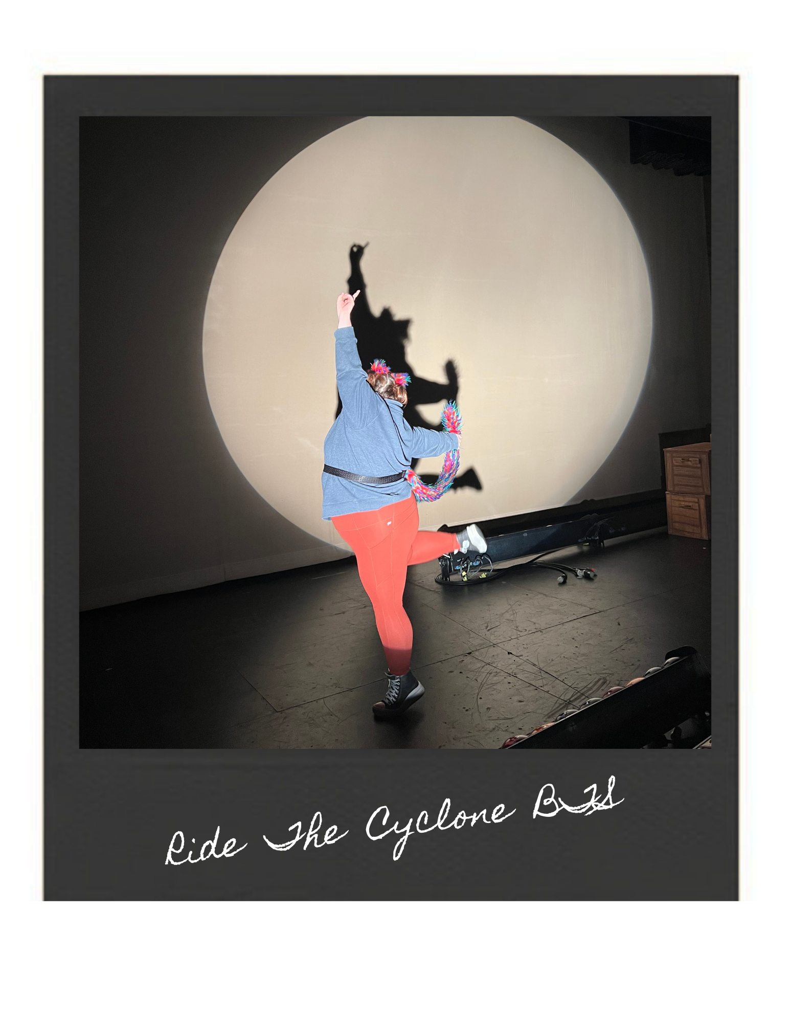 Person in colorful costume, jumping with one leg up, casting a shadow that resembles a tornado on a large screen, with the words "Ride The Cyclone Back" written at the bottom.