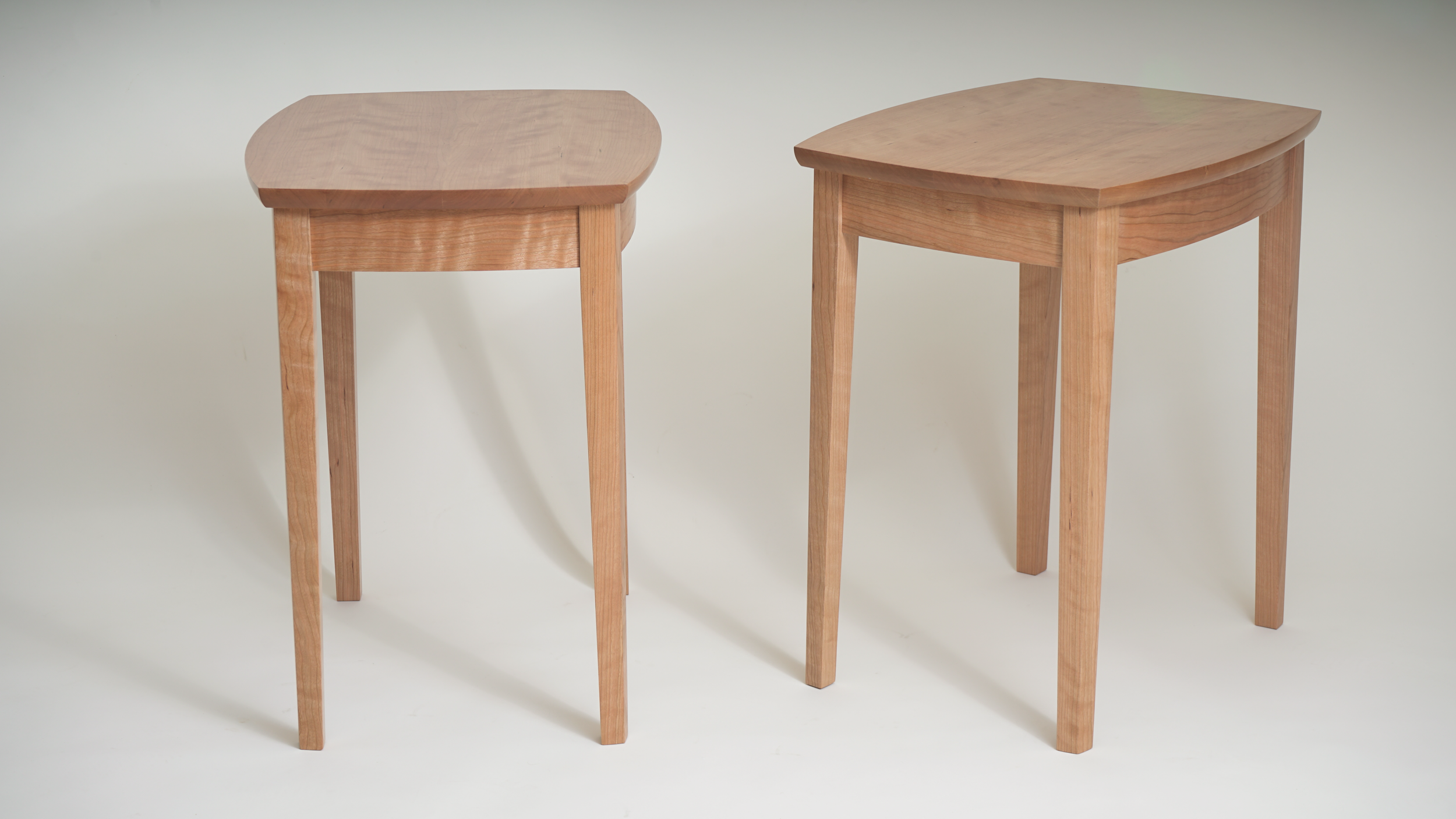 Two wooden tables with curved and rectangular shapes on a white background.