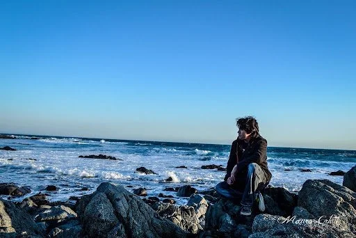Person sitting on a rock at El Tabo, Chile. Mauro Aravena. CC BY-NC-ND 2.0.