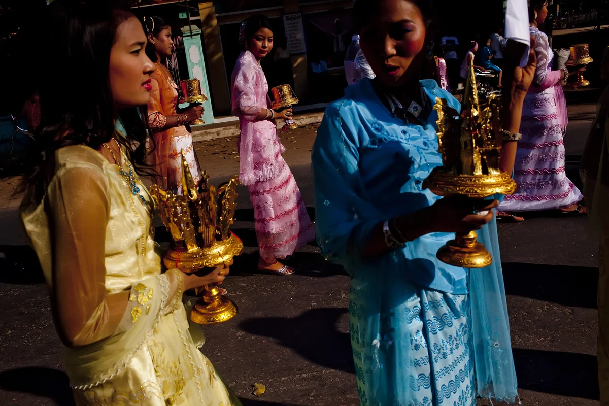  Burmese women pass dressed in traditional clothing pass through the streets of Bagan during a wedding. 