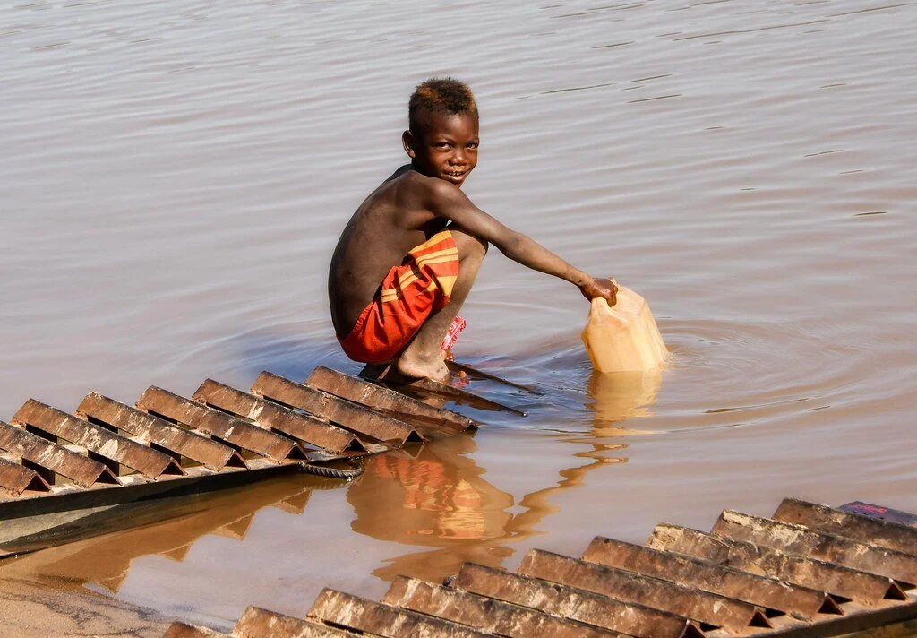Kid getting water from a river