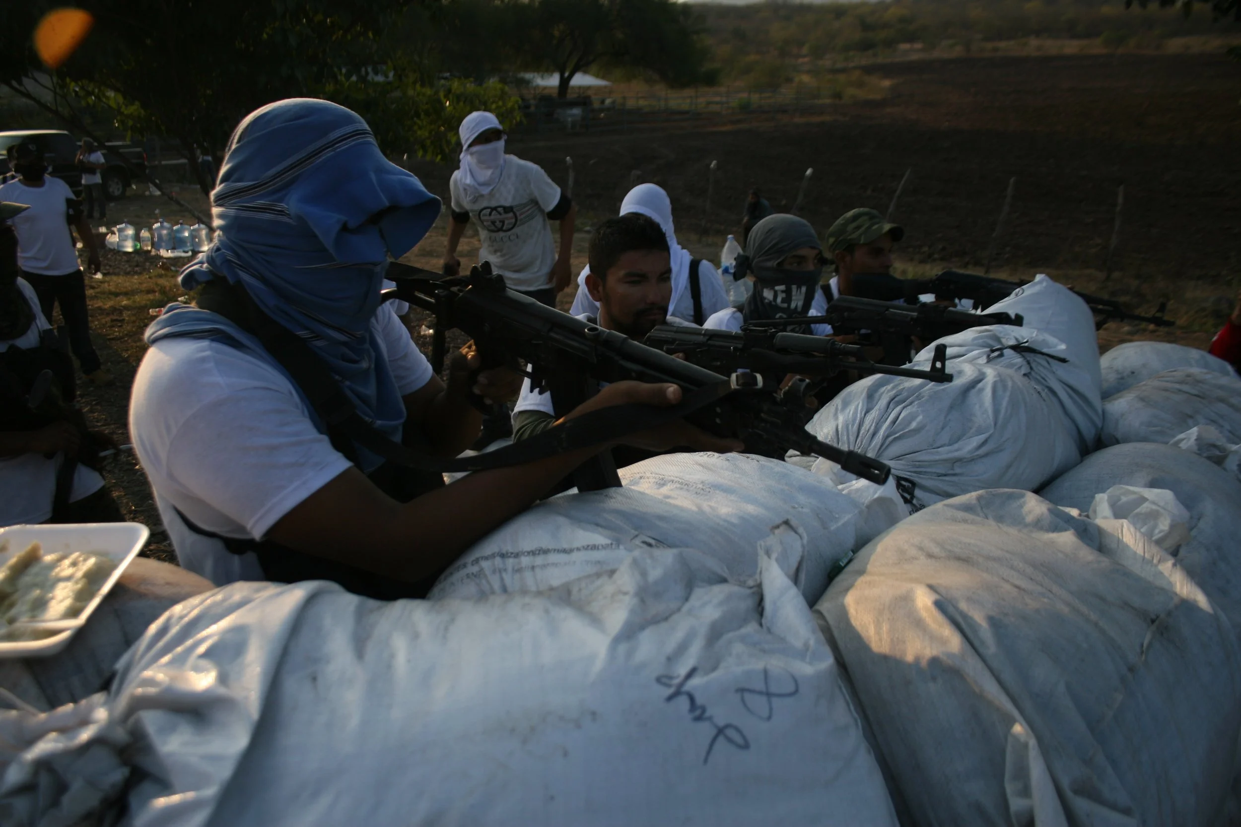 Men with guns shooting over sandbags