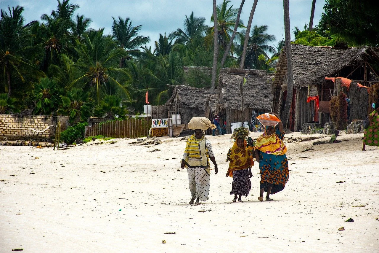 Women walking on beach with bags on their heads