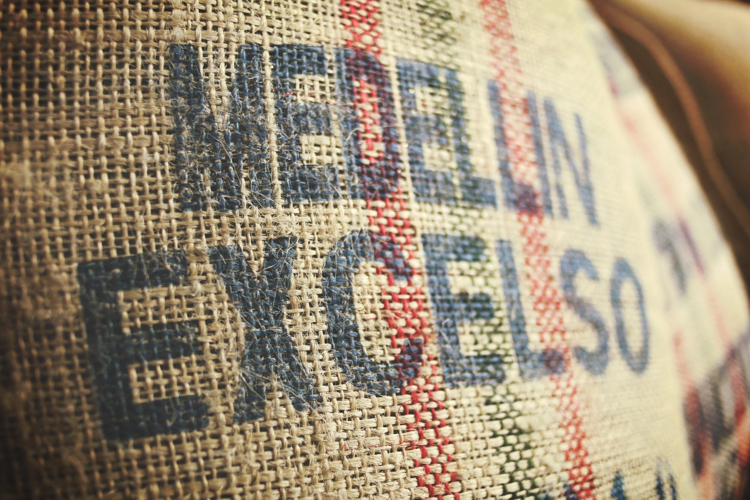 Gros plan d'une toile de jute avec un texte imprimé censuré en bleu, entourée de lignes rouges et vertes.