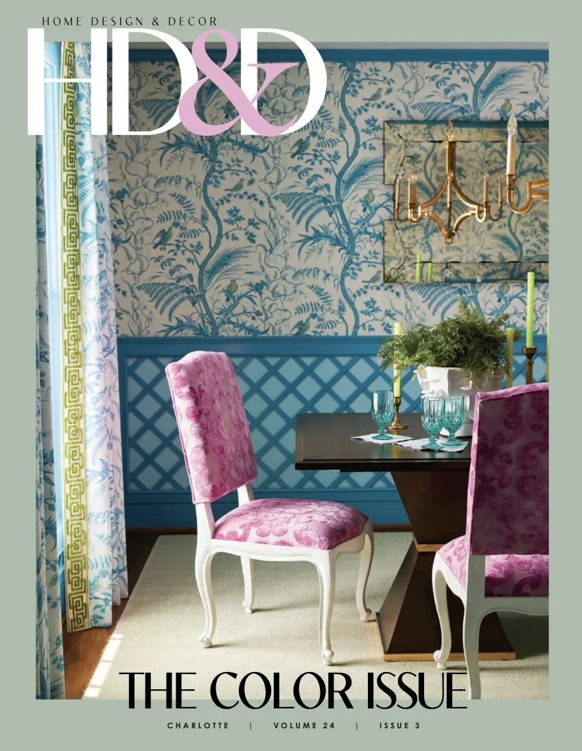 Cover of Home Design & Decor magazine featuring a dining room with pink upholstered chairs, blue wallpaper with botanical pattern, a black table with green candles, and large window with patterned curtains.