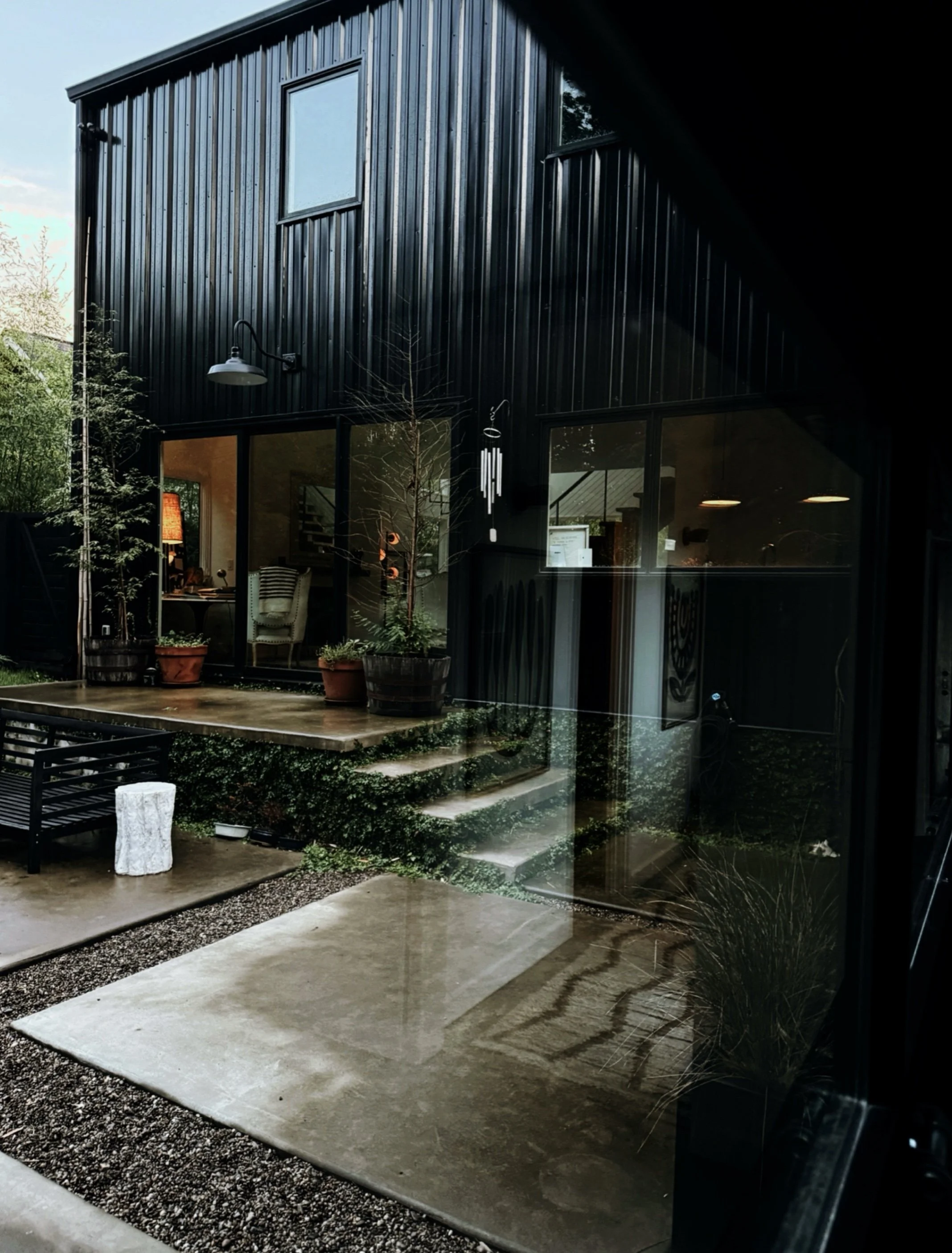 Modern black exterior home on a rainy day with large windows reflecting the surrounding landscape. The personal home of Michel Van Devender.