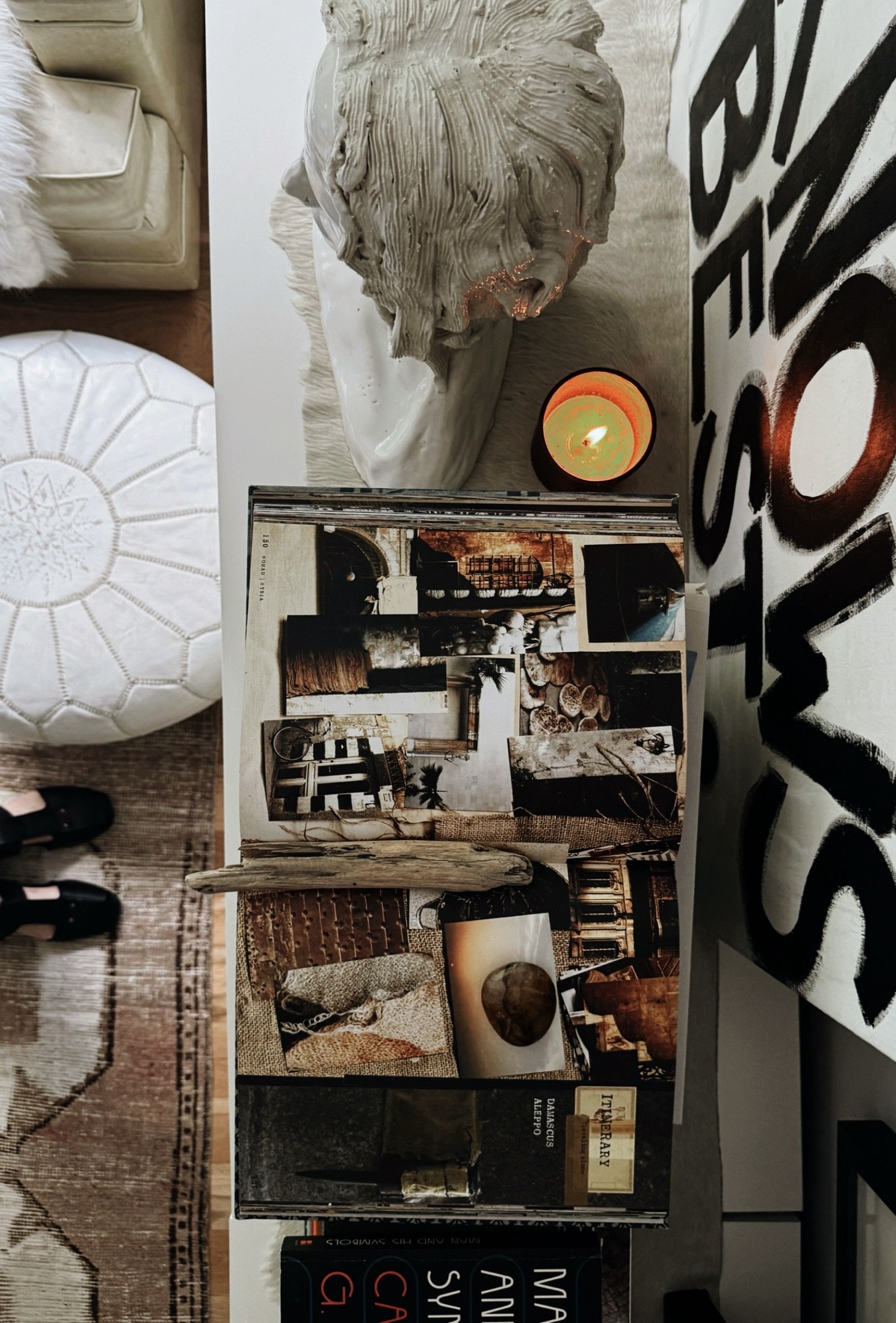 Overhead flatlay of table or dresser with white sculptural head open book candle and design books