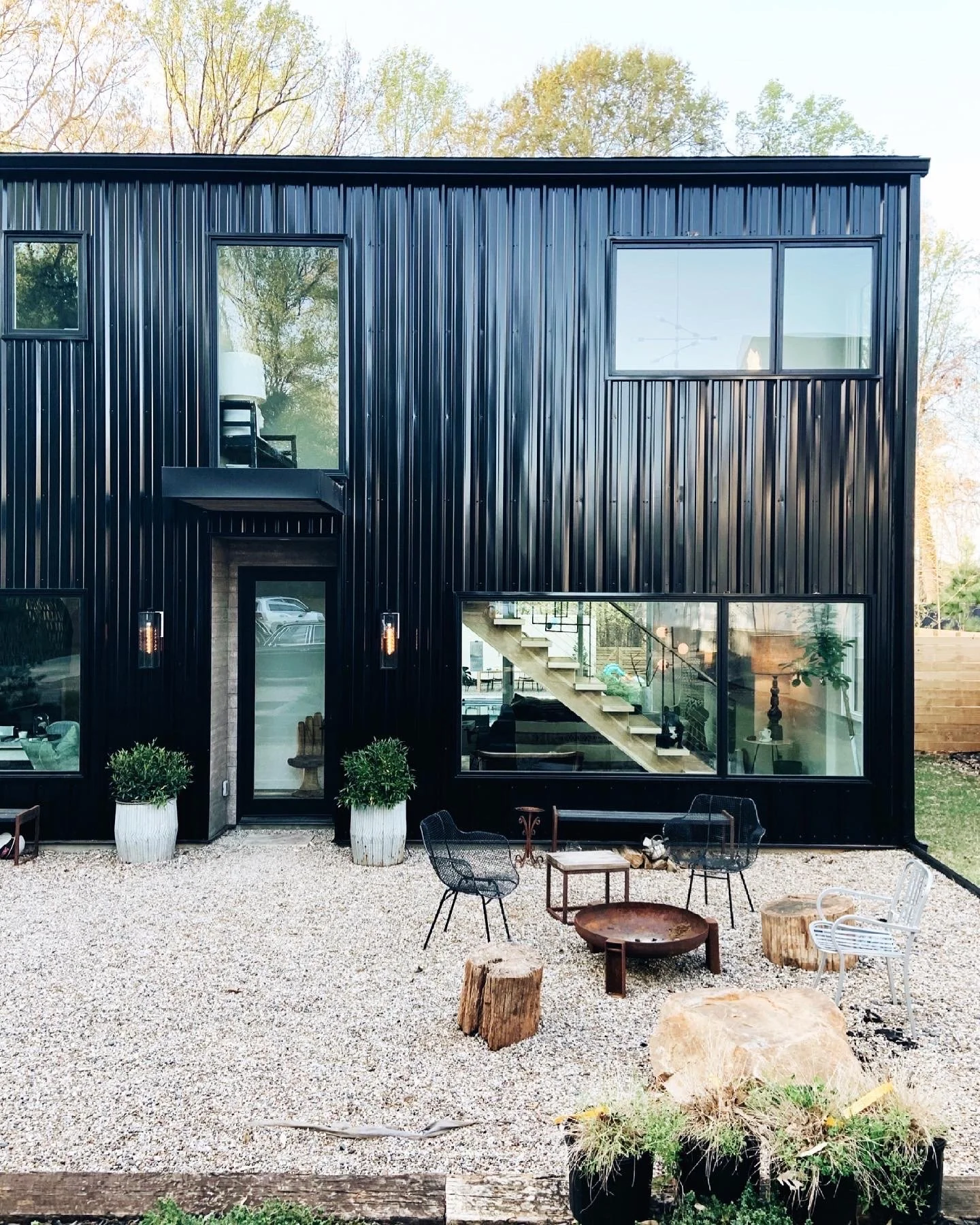 Front view of Michel Van Devender's Charlotte, North Carolina, modern black house with large windows and outdoor seating area with rocks and gravel.
