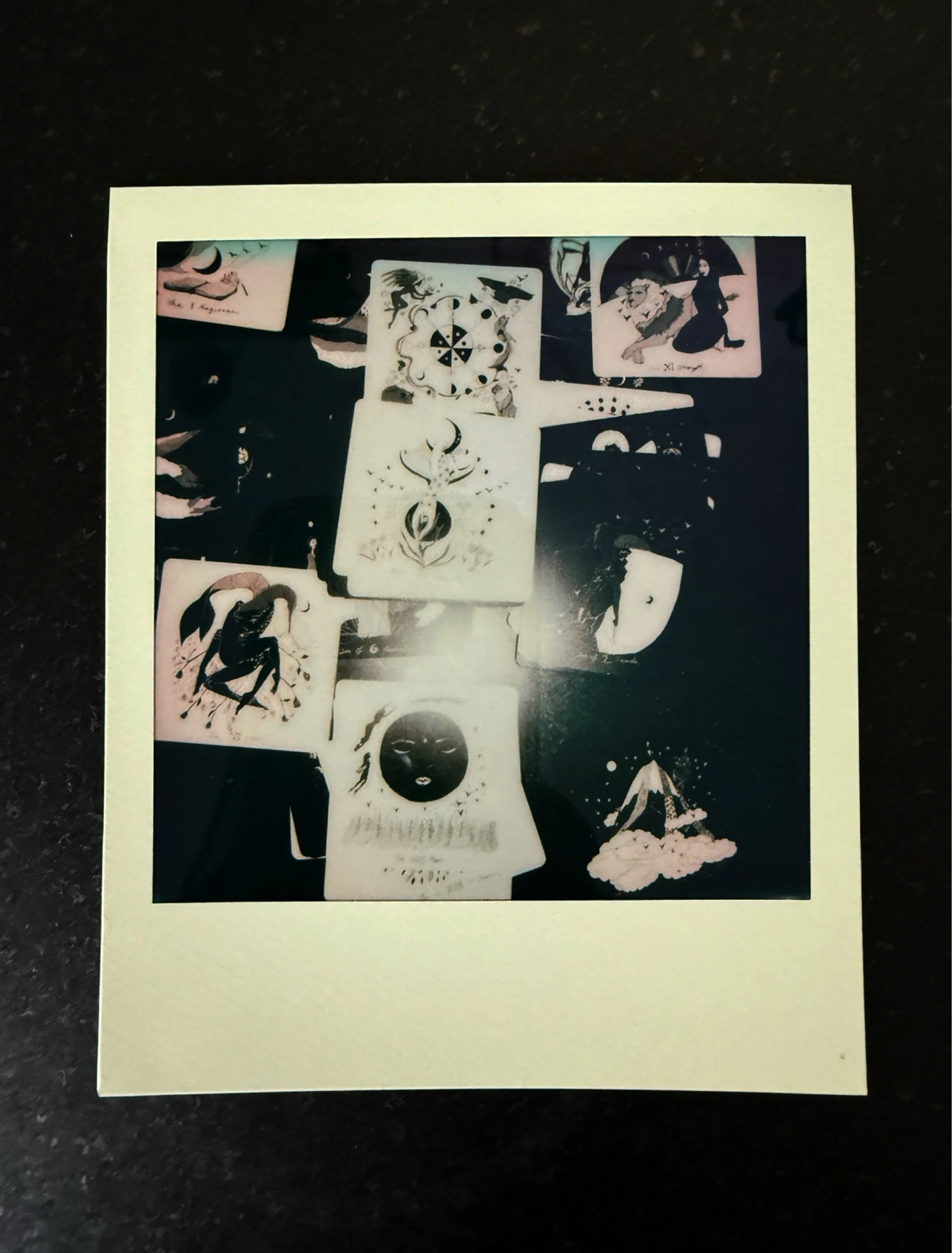 Polaroid photograph of a tarot card spread laid out on a dark surface, multiple illustrated cards visible
