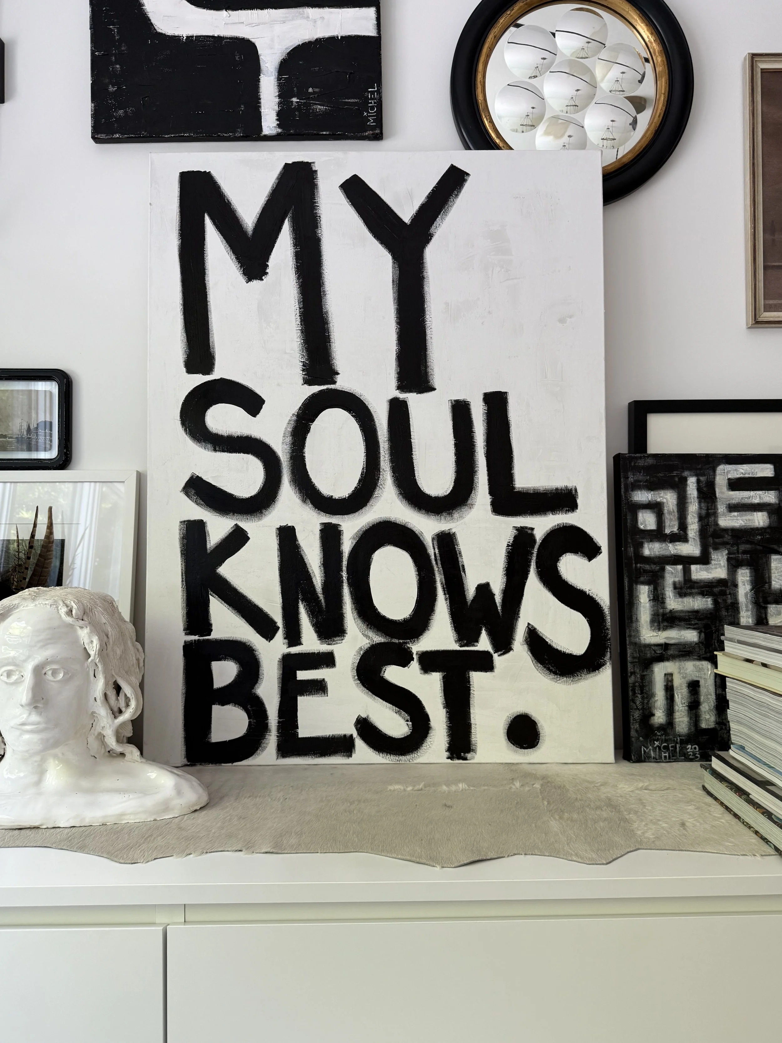 Art studio vignette featuring a sculptural bust, artwork, and a sign reading "My Soul Knows Best." by Michel Van Devender.