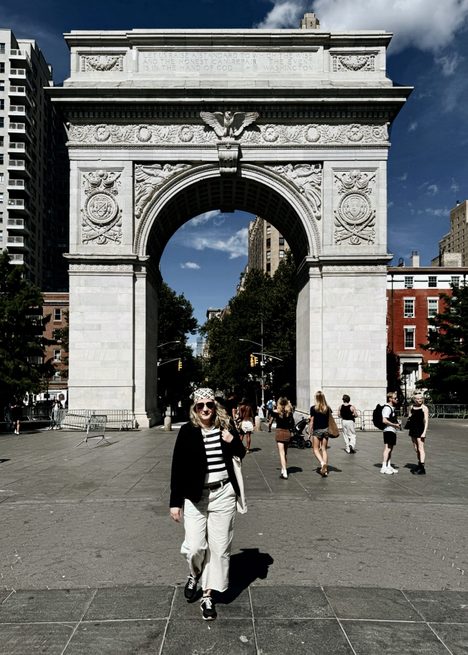 Washington Square Arch framed by trees and city buildings in New York City.