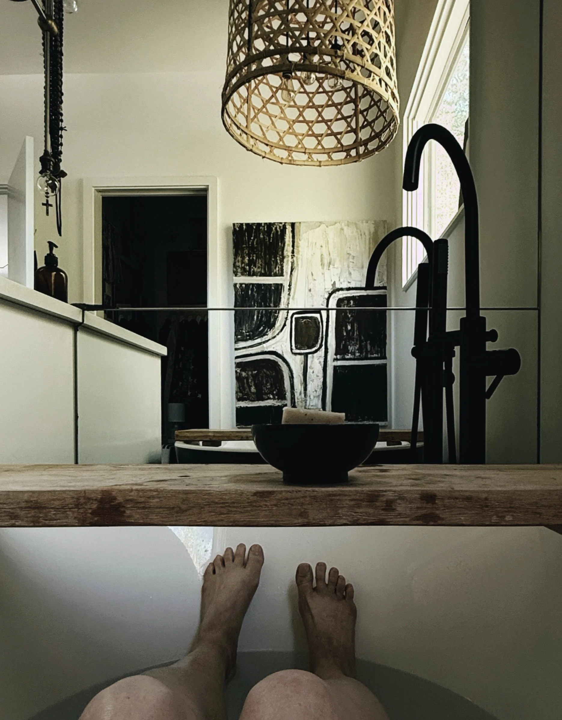 modern home of michel van devender primary bathroom with abstract art, black bathroom fixtures and organic lighting.