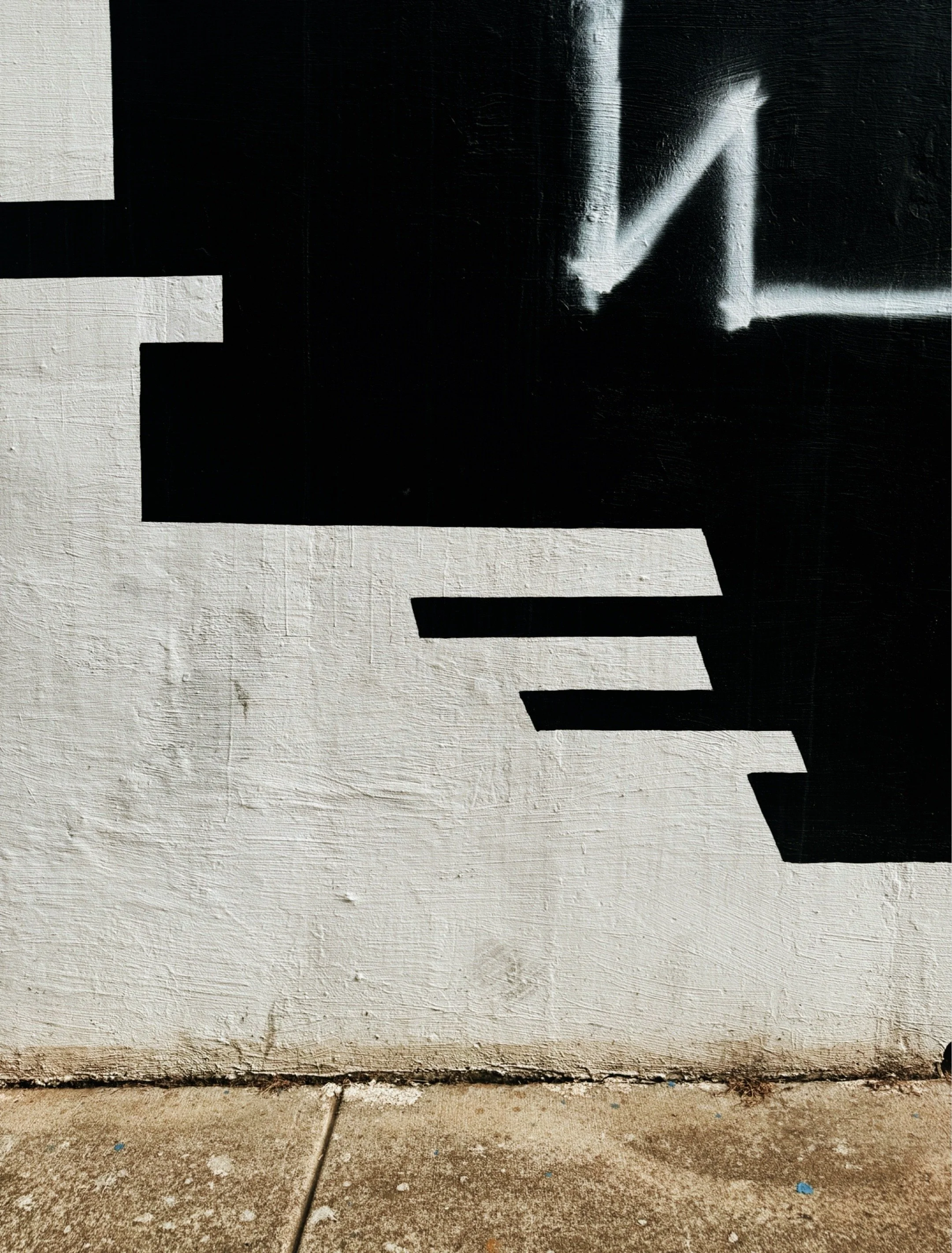 Black and white mural featuring abstract shapes and graphic patterns on an exterior wall.