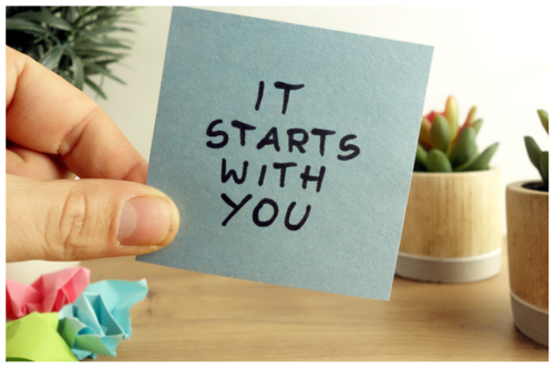 post-it note says it starts with you with hand holding it