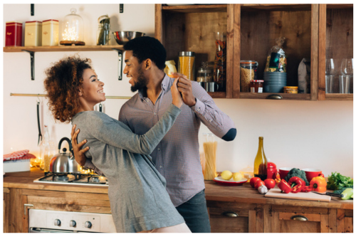BIPOC couple intimate dancing in kitchen cooking happy smiling