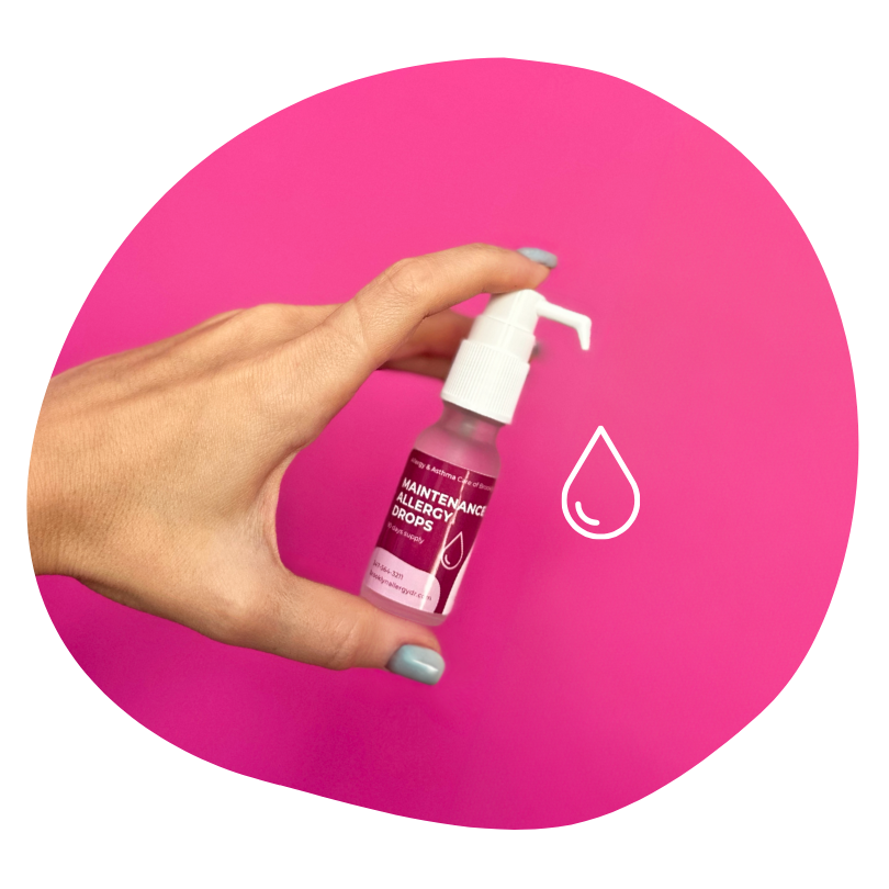 Hand holding a spray bottle labeled maintenance allergy drops against a pink background, with a white droplet icon nearby.