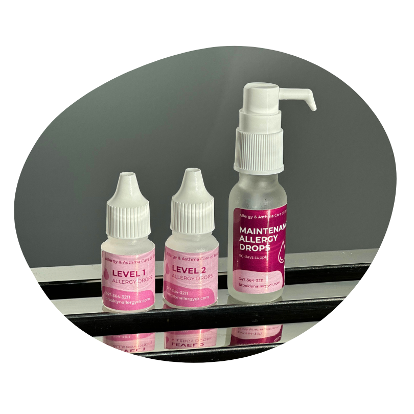 Three allergy drop bottles on a shiny surface, labeled Level 1, Level 2, and Maintenance Allergy Drops