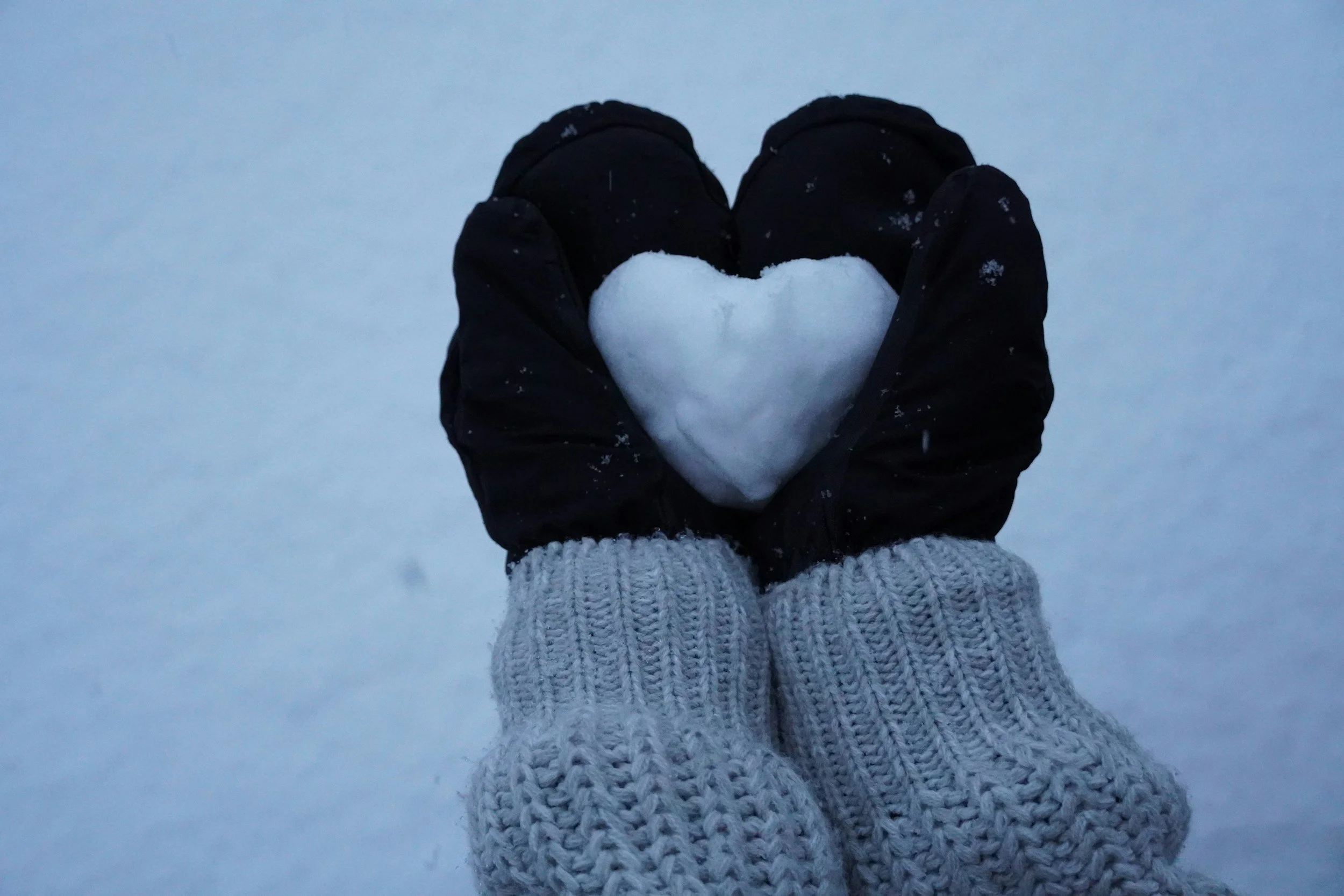 person holding a snowball in the shape of a heart
