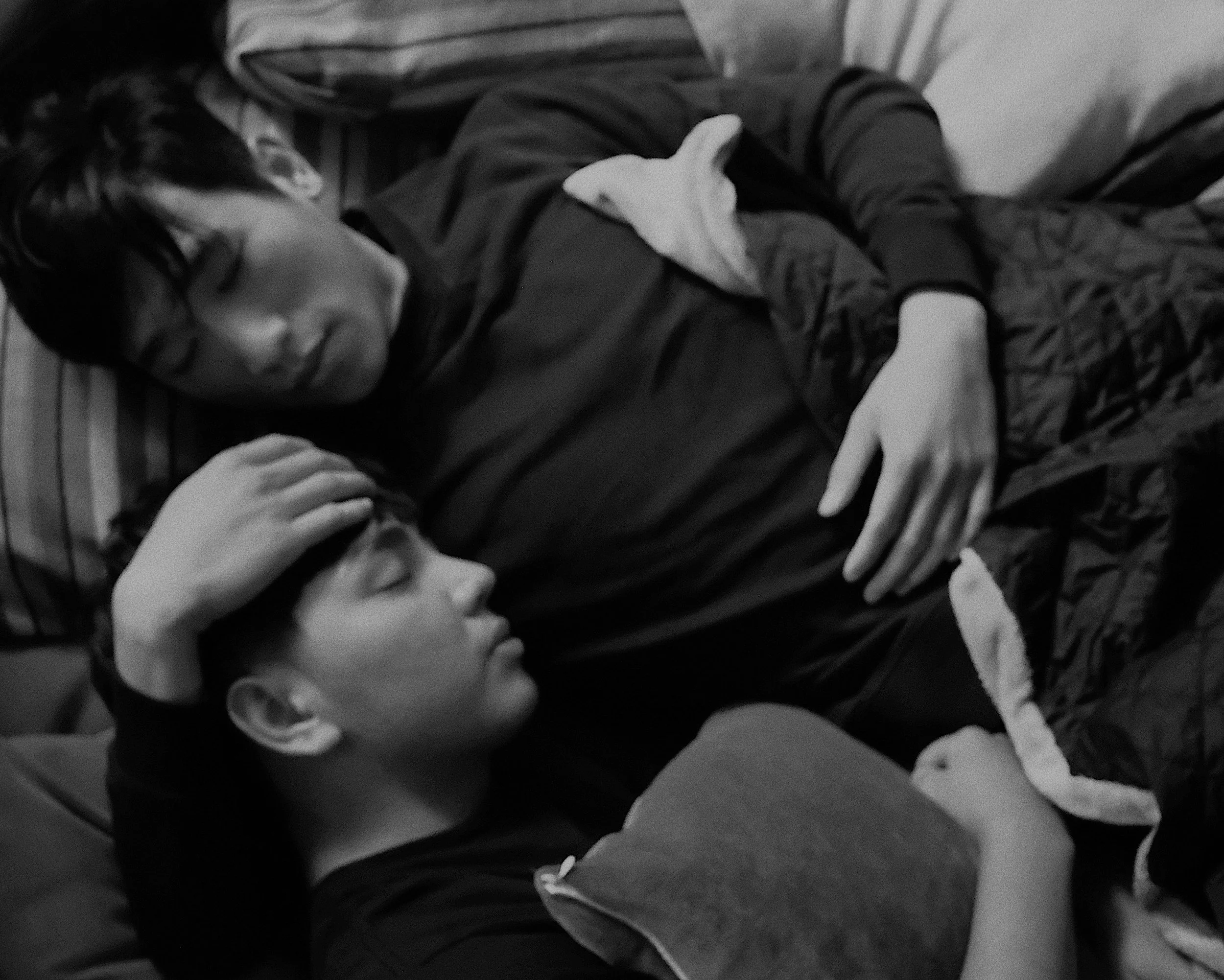 same sex couple laying bed cuddling