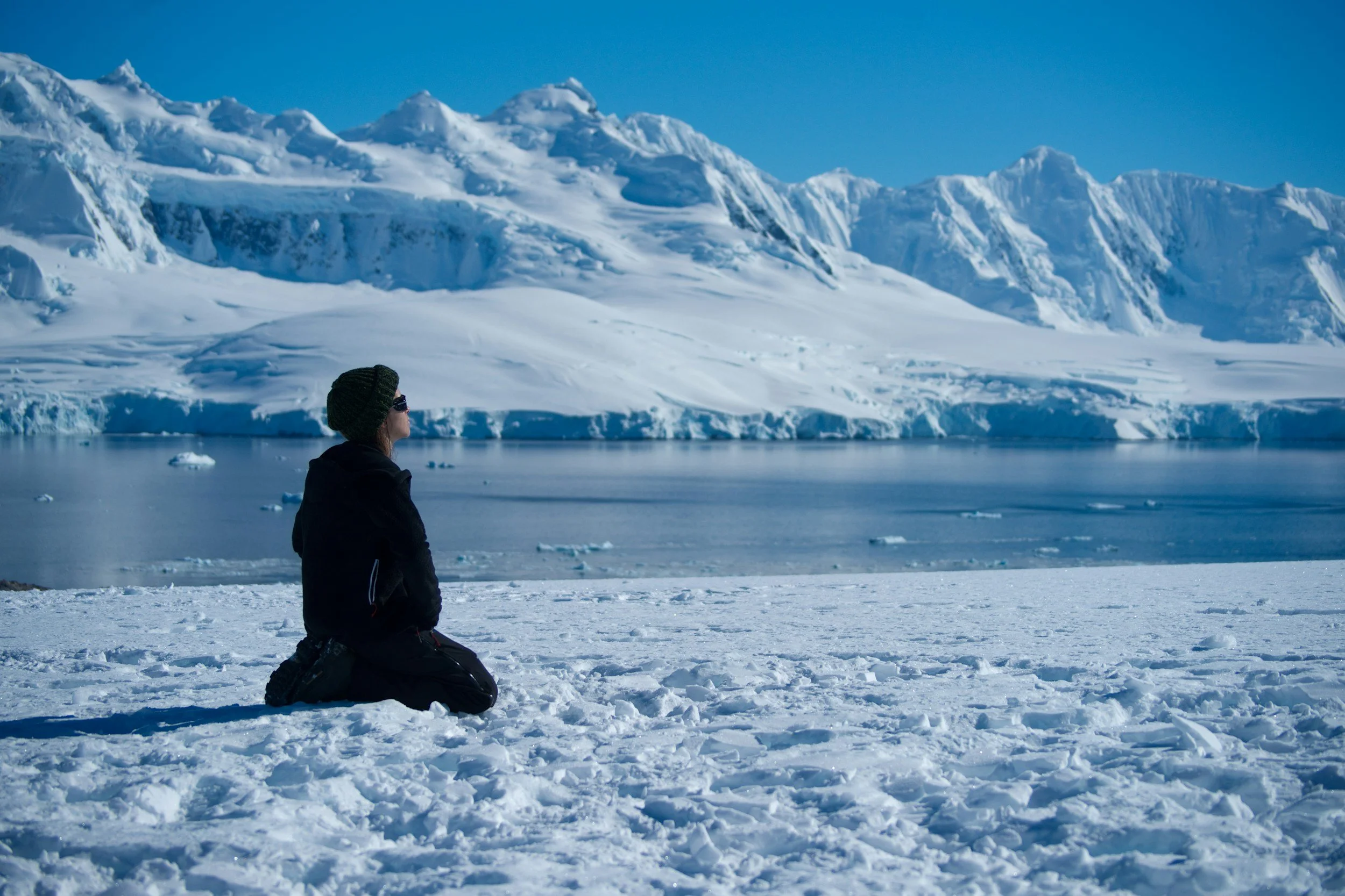 person kneeling in the snow looking at the scenery