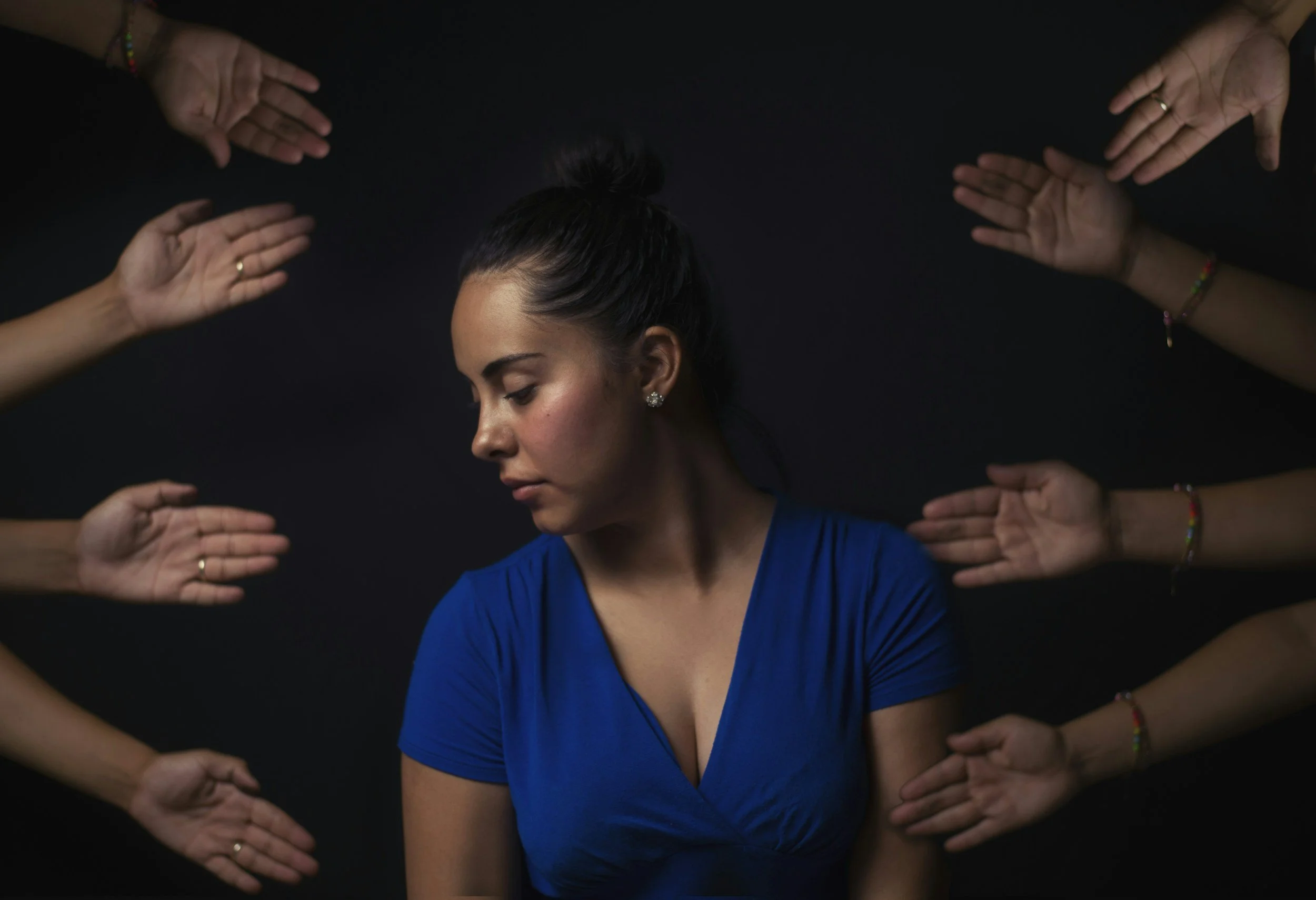 woman of color with all kinds of hands around her