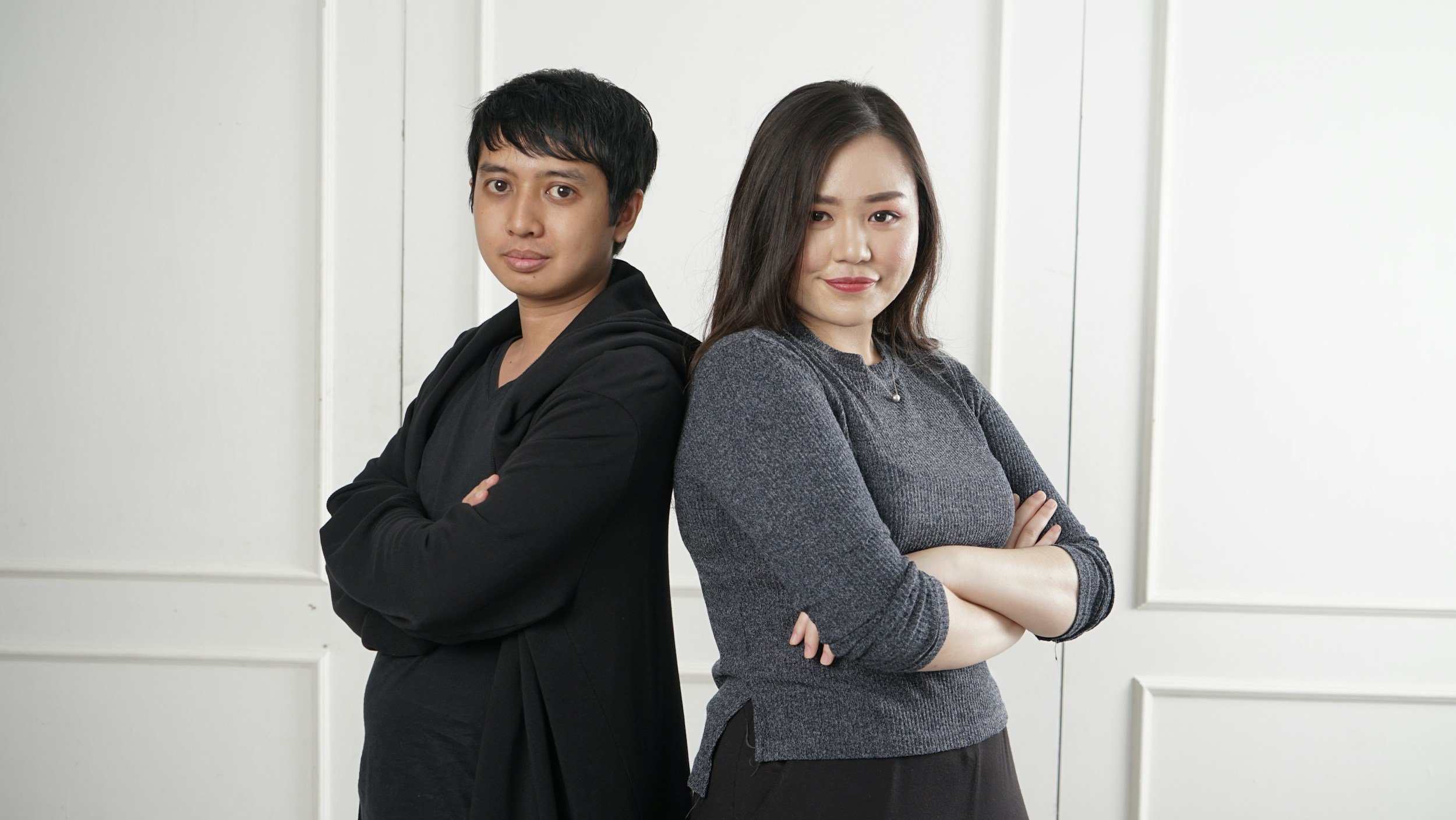 couple standing back to back with their arms crossed
