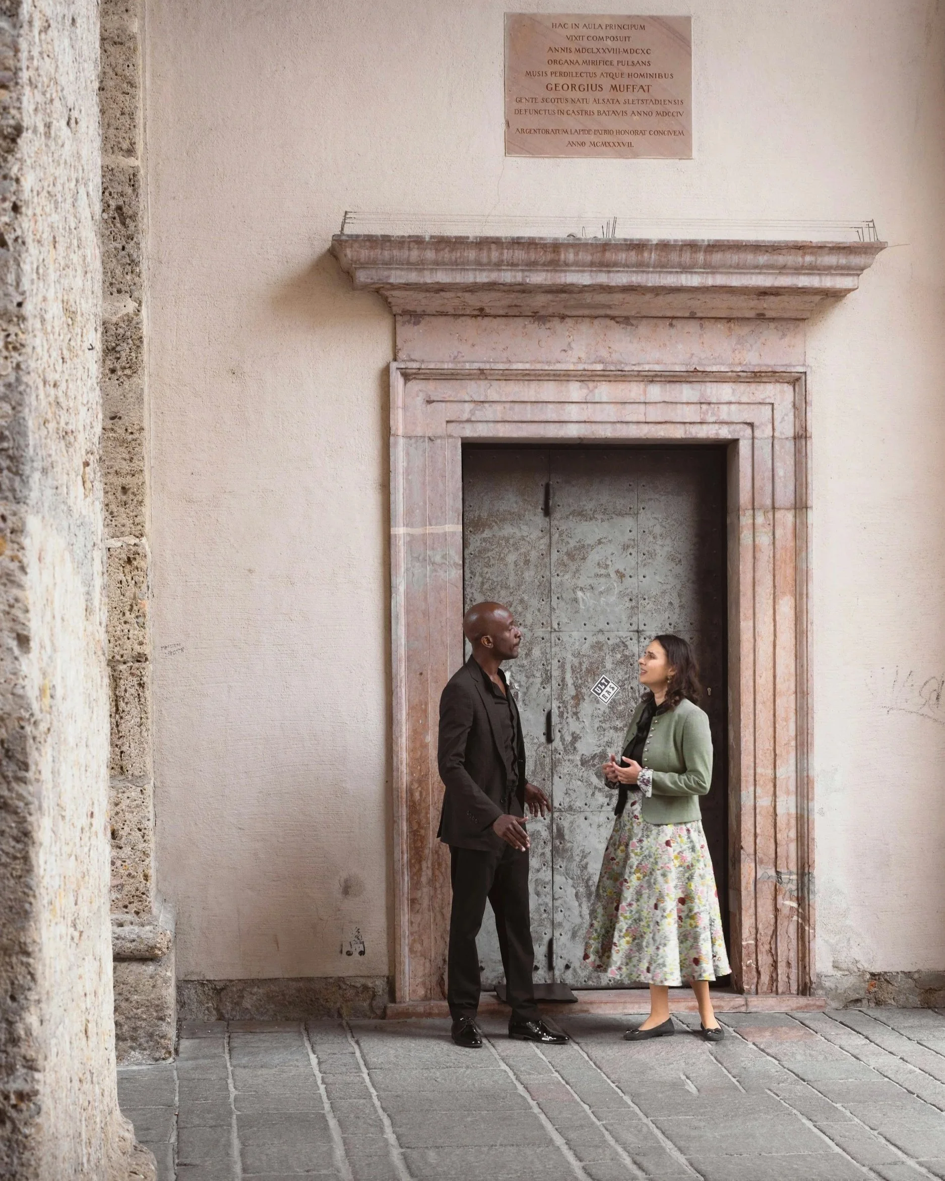 racial couple talking in front of a sealed off door of Georgius Muffat