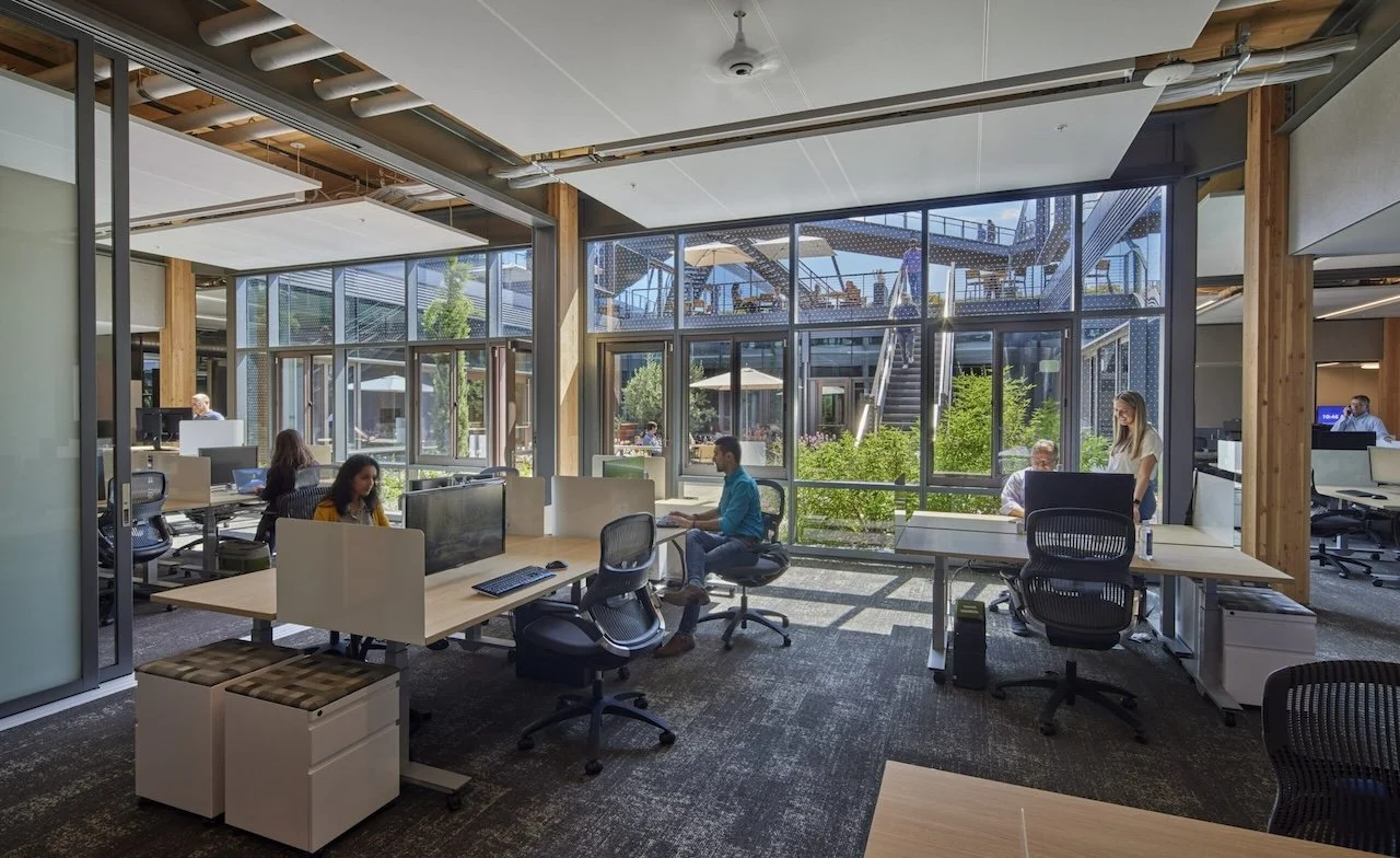 Open office with broad courtyard view and small groups of desks.